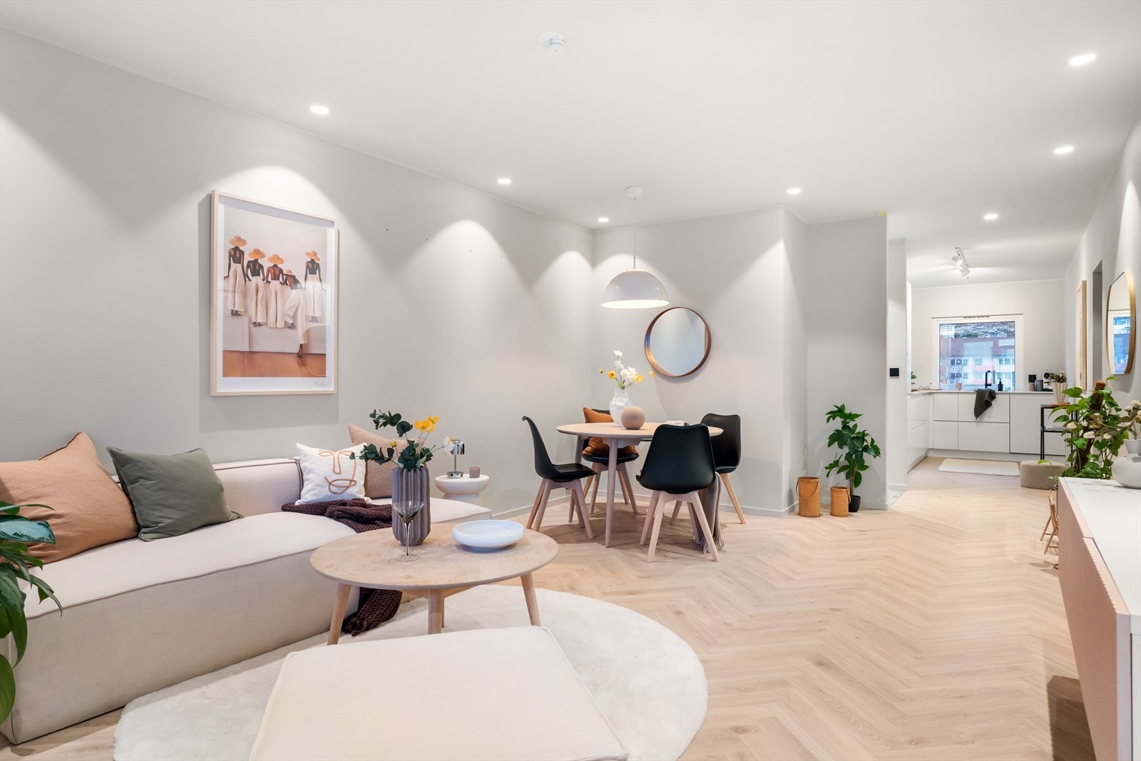 Lys og luftig åpen stue/kjøkken-løsning med fiskebenslaminat på gulvene og lys malte vegger. Galleribilde