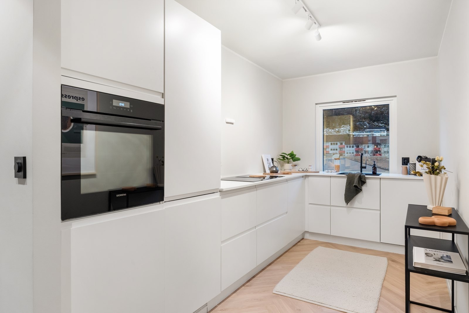 Integrerte hvitevarer som induksjon platetopp med integrert avtrekk, steikeovn, oppvaskmaskin og kombiskap (kjøl/frys). Galleribilde