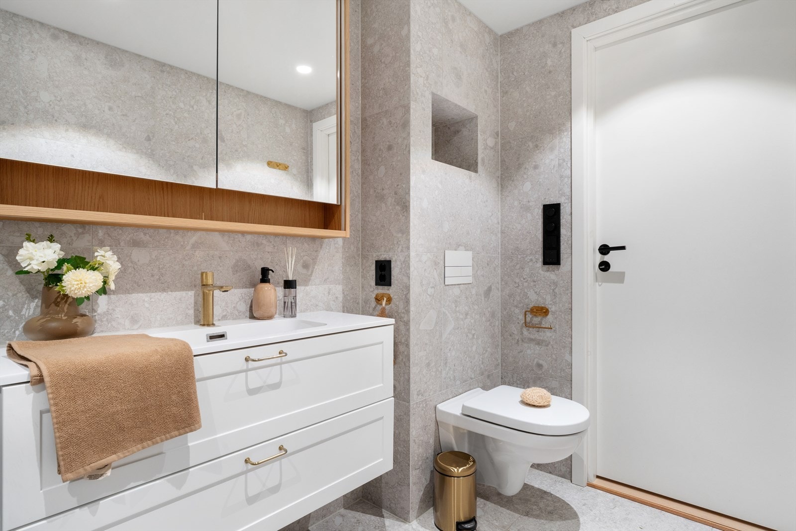 Badet er innredet med vegghengt toalett, benkeskap med servant, dusjvegg i glass og opplegg for vaskemaskin. Galleribilde