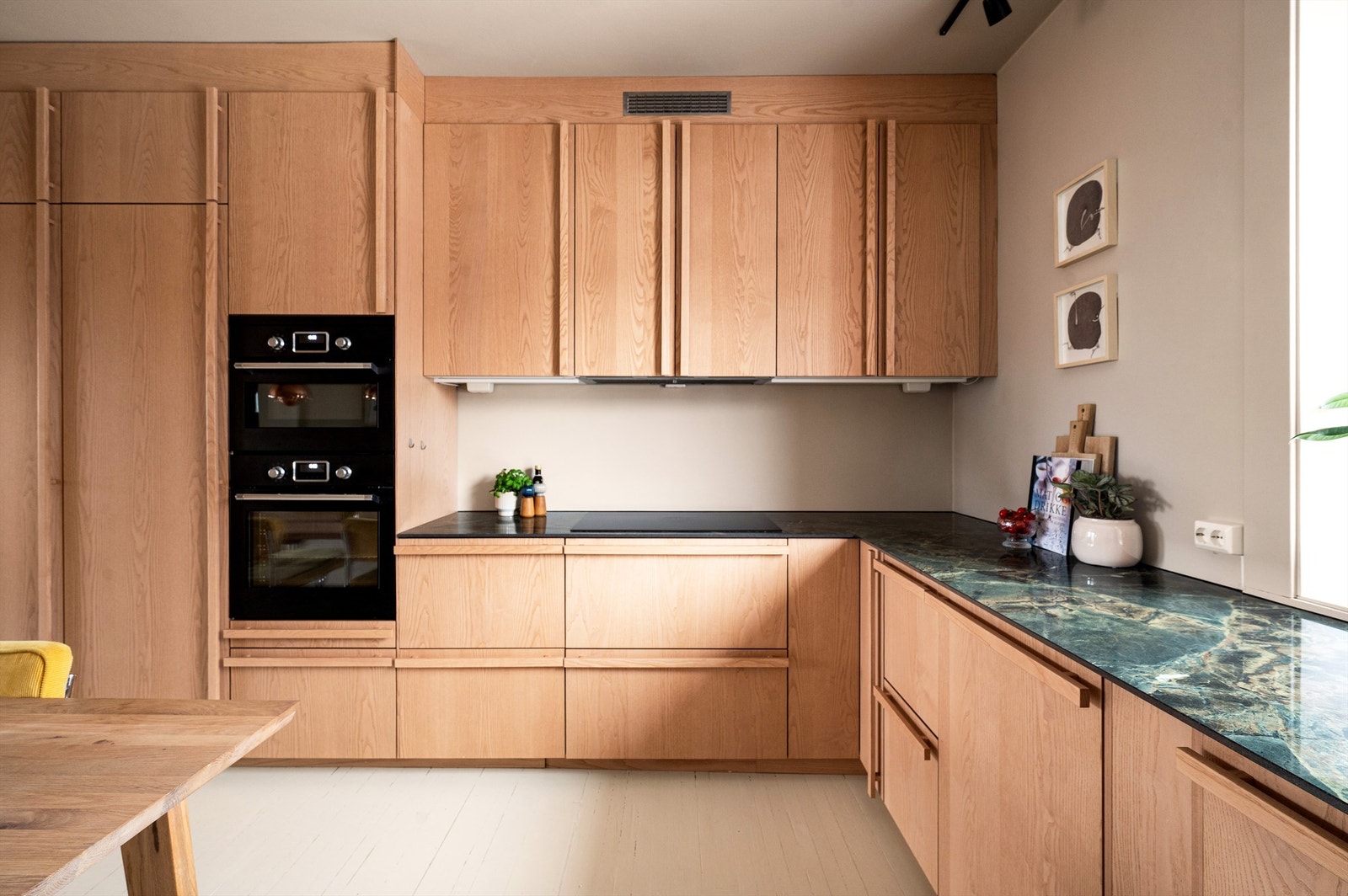 Kjøkkeninnredningen har glatte fronter og en solid benkeplate av lekker keramisk stein med vask av rustfritt stål. Galleribilde