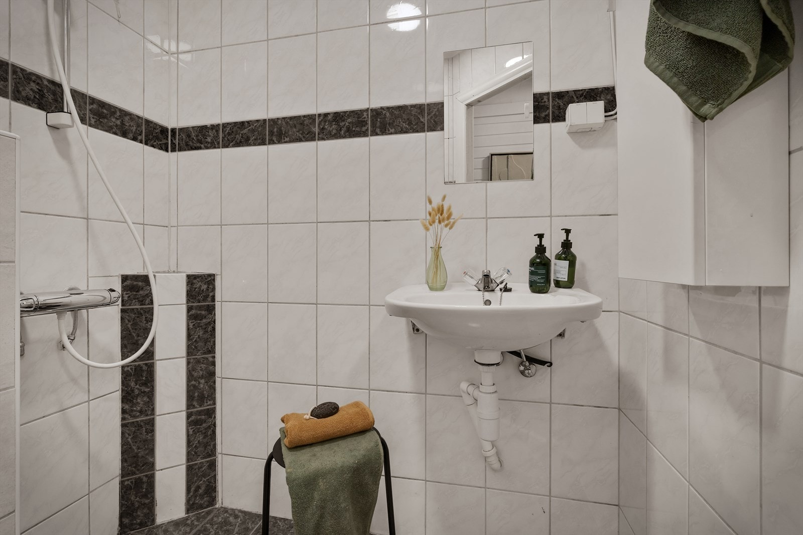 Rommet er inredet med servant, veggmontert toalett og dusjgarnityr på vegg. Galleribilde