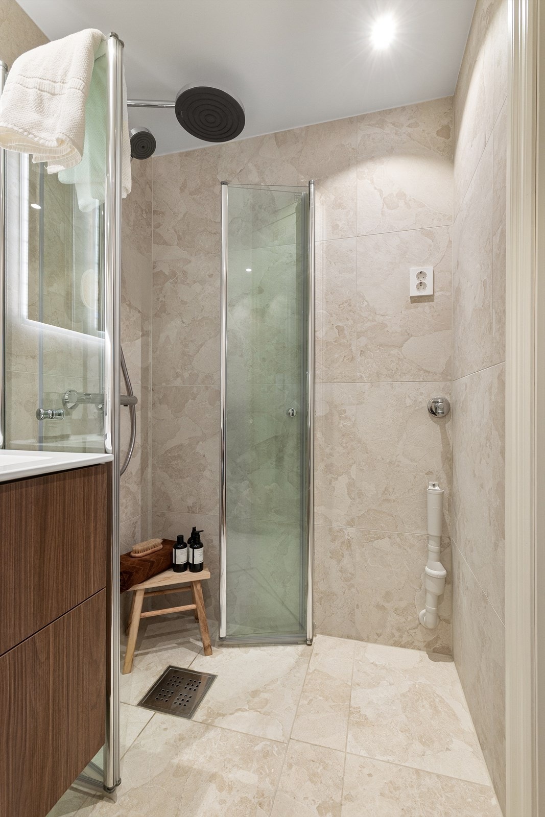 Innredning bestående av vegghengt toalett, servant med skuffer og dusjhjørne med glassdør. Det er opplegg for vaskemaskin. Galleribilde