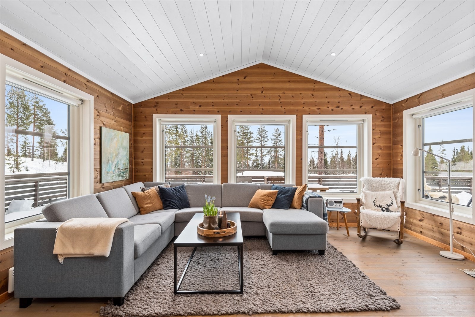 Lys stue med åpen himling og godt med vindusflater, som slipper lys og naturen inn i rommet. Galleribilde