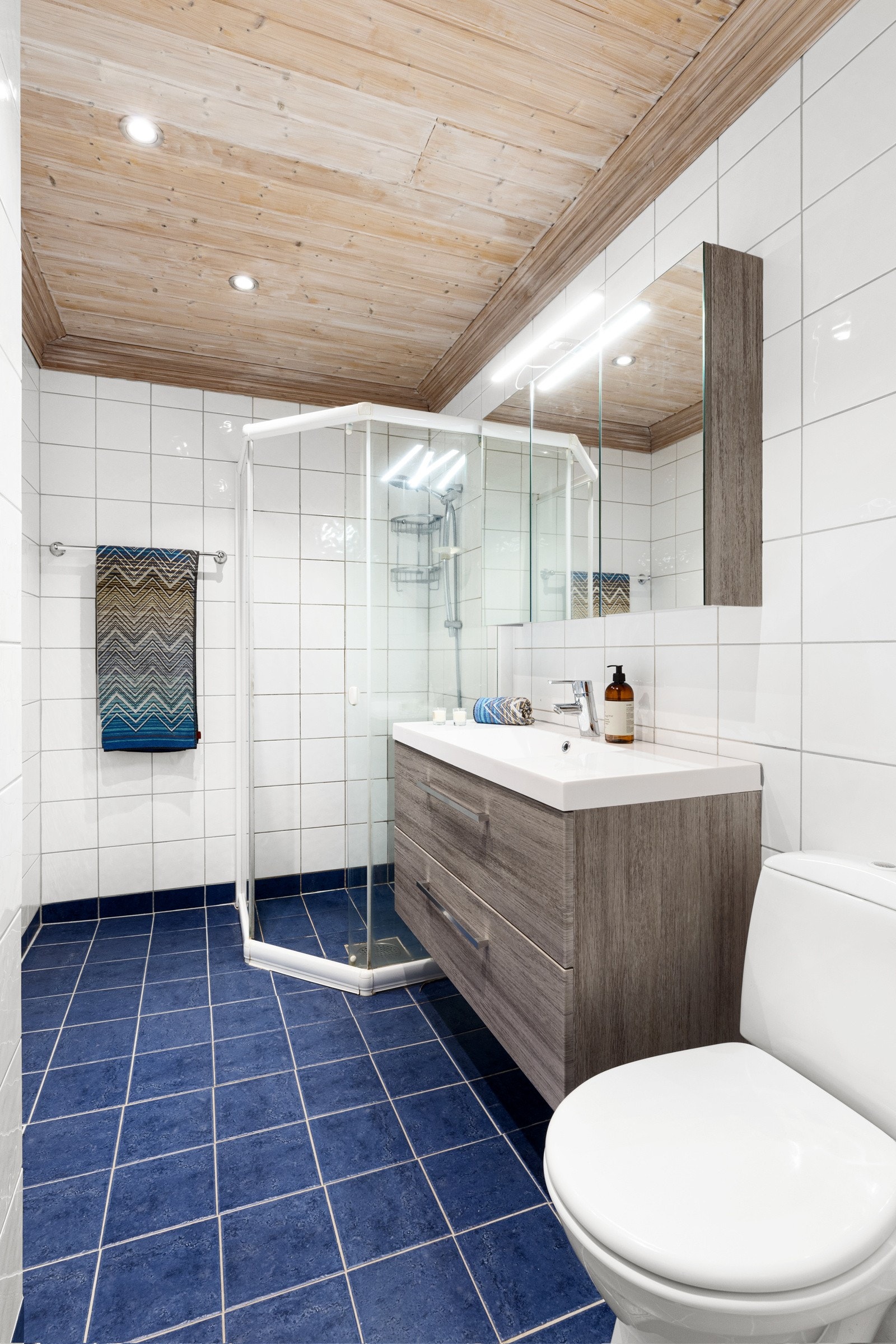 Badet i boligens underetasje er pent flislagt med varmekabler i gulv, stilren innredning og himling med downlights. Galleribilde