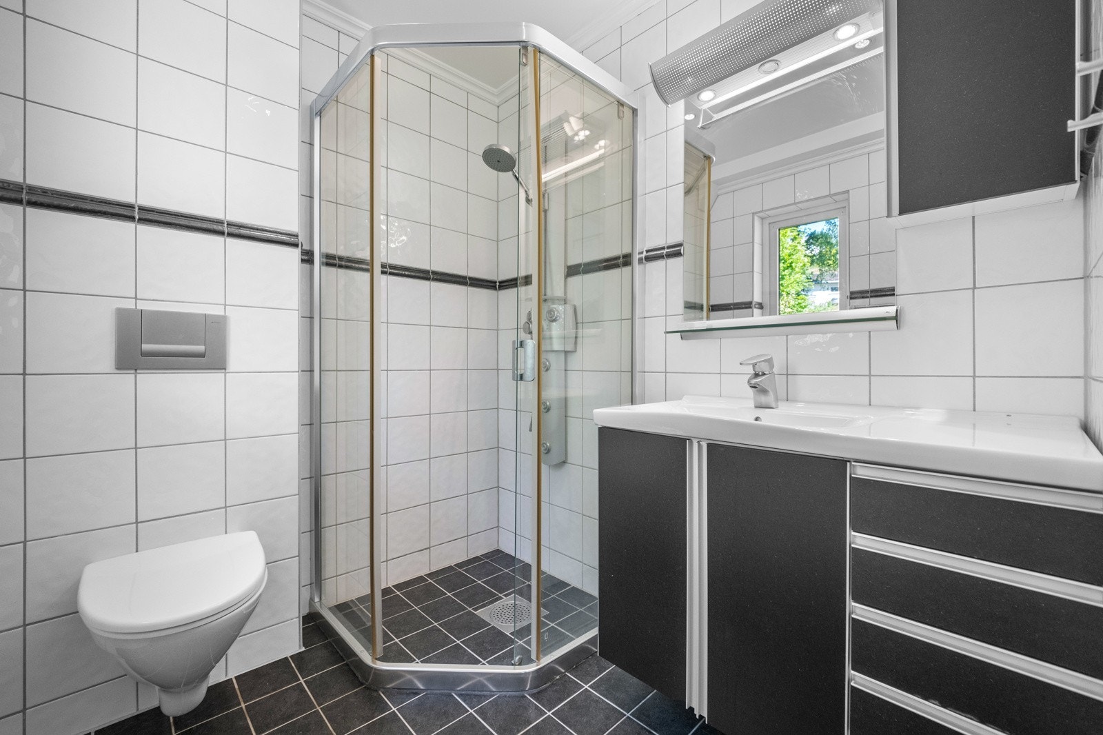 Bad i 1.etasje med wc, dusjhjørne og servant med innredning. Galleribilde