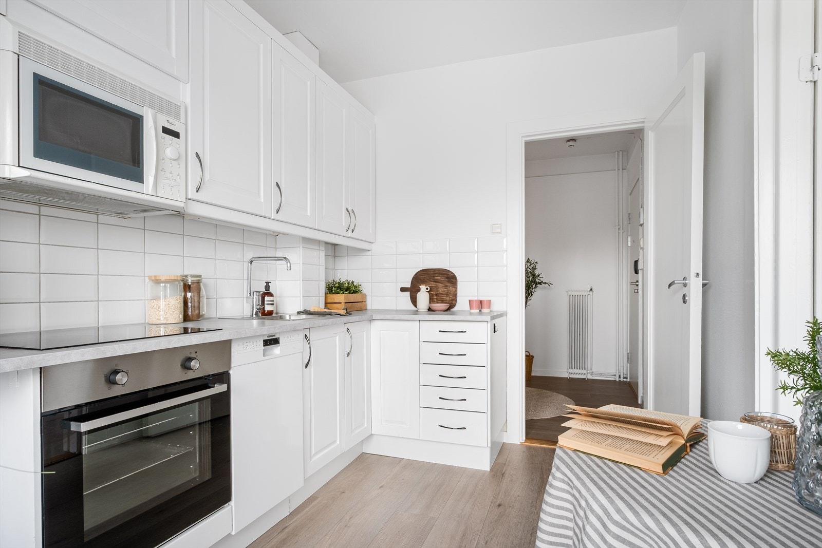 Profilert innredning, gesimslist, lyslist, armatur, fliser over benk, laminat benkeplate med nedfelt stålkum og keramisk topp, integrert komfyr, oppvaskmaskin (smal type), micro. Det er kjøkkenventilator med kullfilter. Galleribilde