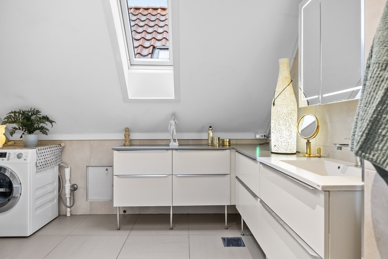 Videre finner du servantskap med benkeplate, underskap, speilskap og høyskap som gir rikelig med oppbevaringsplass. Her er også opplegg for vaskemaskin. Rommet har naturlig avtrekk i taket og tilluft via dør, noe som sikrer et godt inneklima. Galleribilde