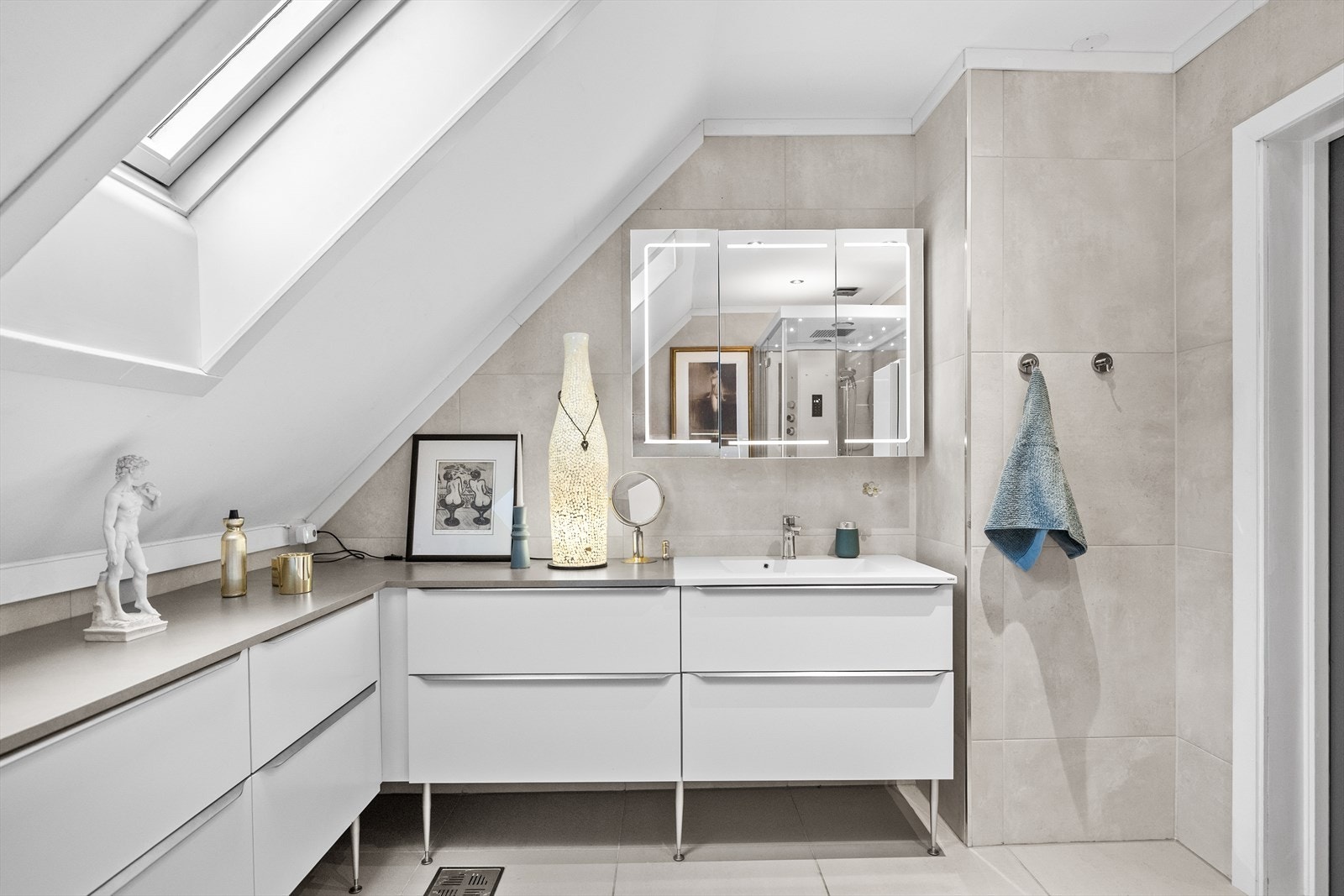 Baderommet ble renovert i 2020 og fremstår som moderne, delikat og svært innbydende. Rommet har flislagt gulv med elektriske varmekabler som gir en behagelig varme, og veggene er kledd med flotte fliser i tidløst design. Galleribilde