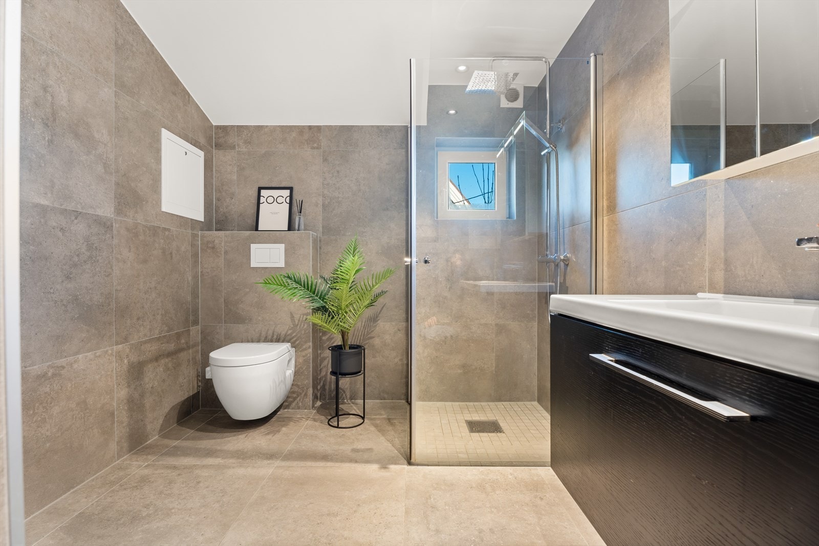 Badet er innredet med flis på gulv og vegger, og malt gips med spotter i himlingen. Badet ble renovert i 2024, i følge eier. Galleribilde