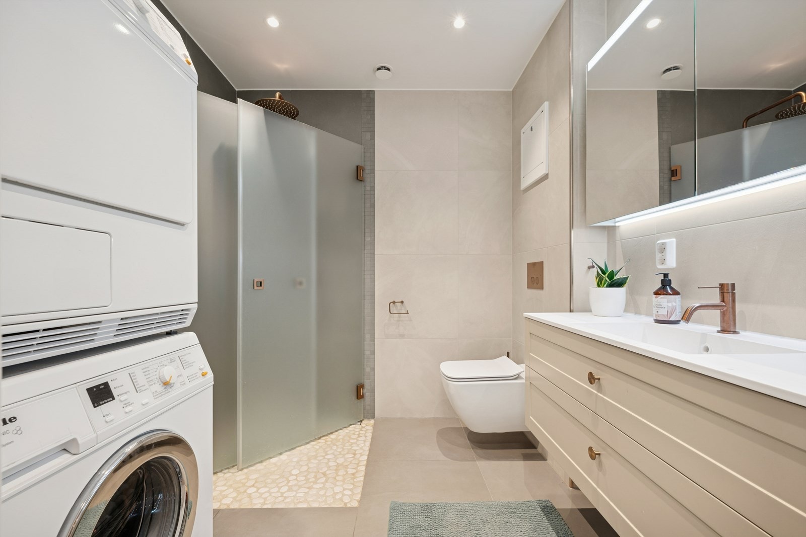 Baderommet har flislagte vegger og malt himling med innfelte downlights. Rommet varmes opp ved bruk av elektriske varmekabler. Galleribilde