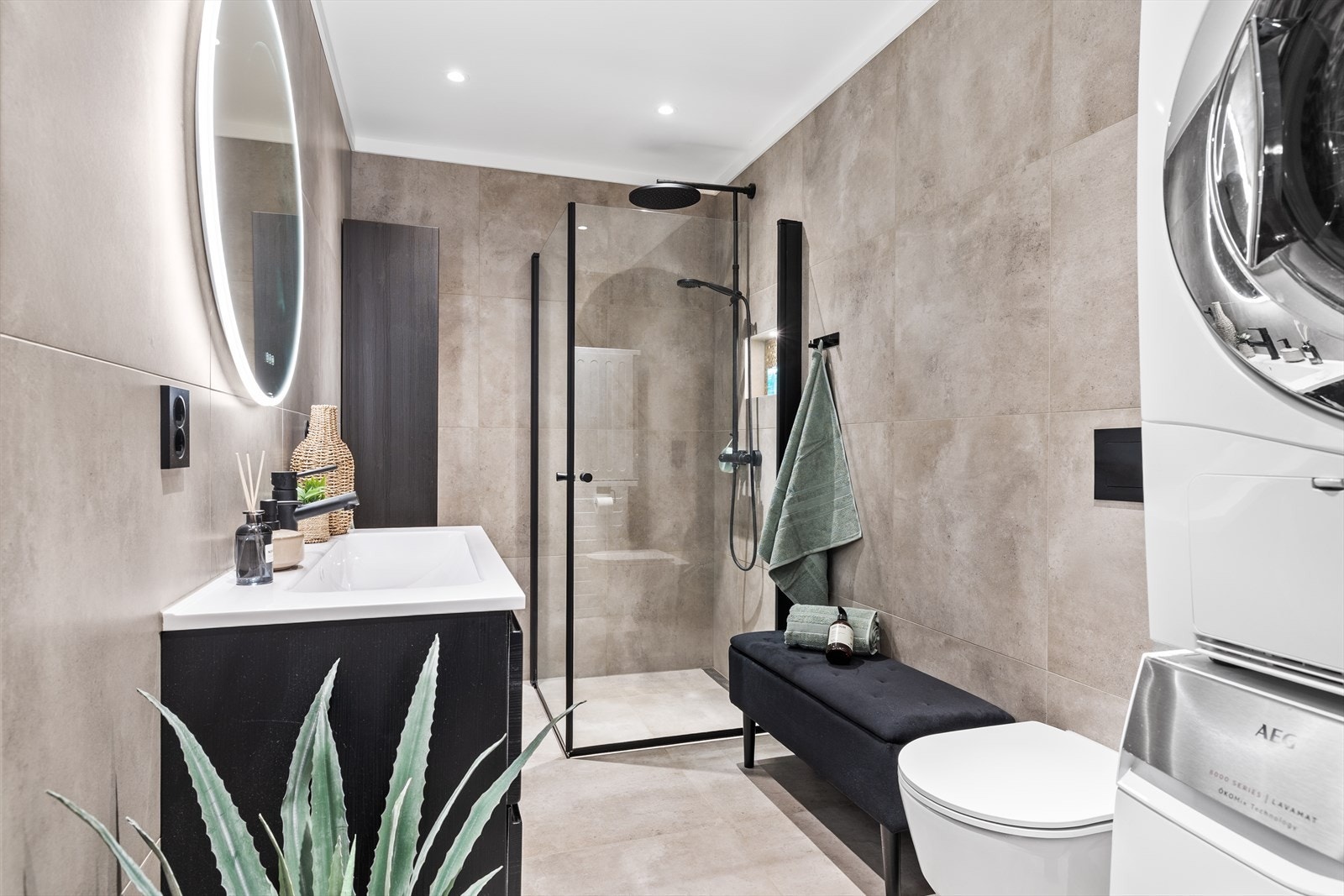 Flislagte vegger og gulv gir badet et moderne og robust utseende. Med lekre detaljer som takdusj og lys i dusjhyllen. Galleribilde