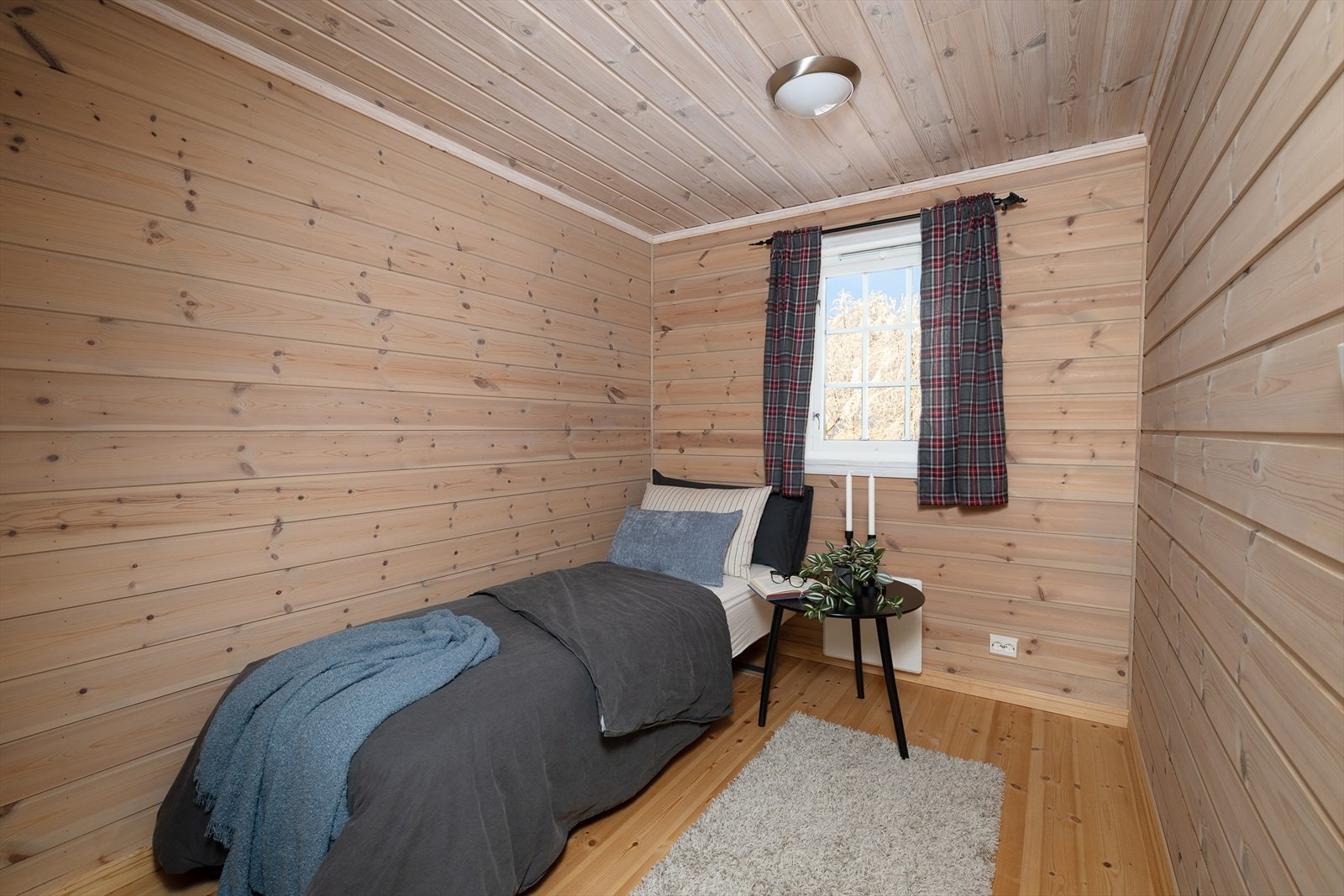 Et av to soverom i andre etasje, begge med furugulv og lyse panelvegger. Galleribilde