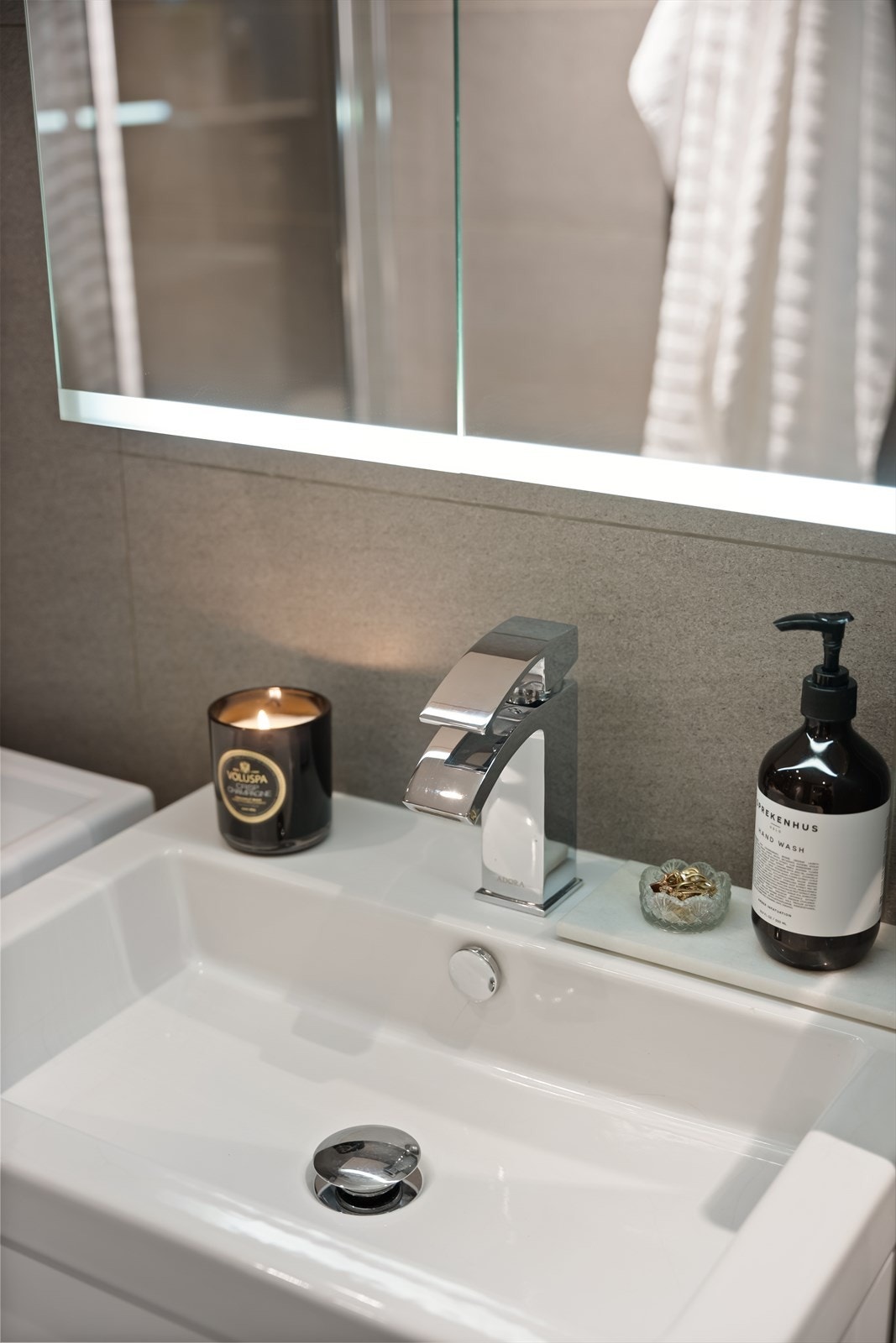 Innredningen består av servant med skuffeseksjon, speilskap, vegghengt toalett, dusjhjørne med fast glassvegg og dør, samt opplegg for vaskemaskin. Galleribilde