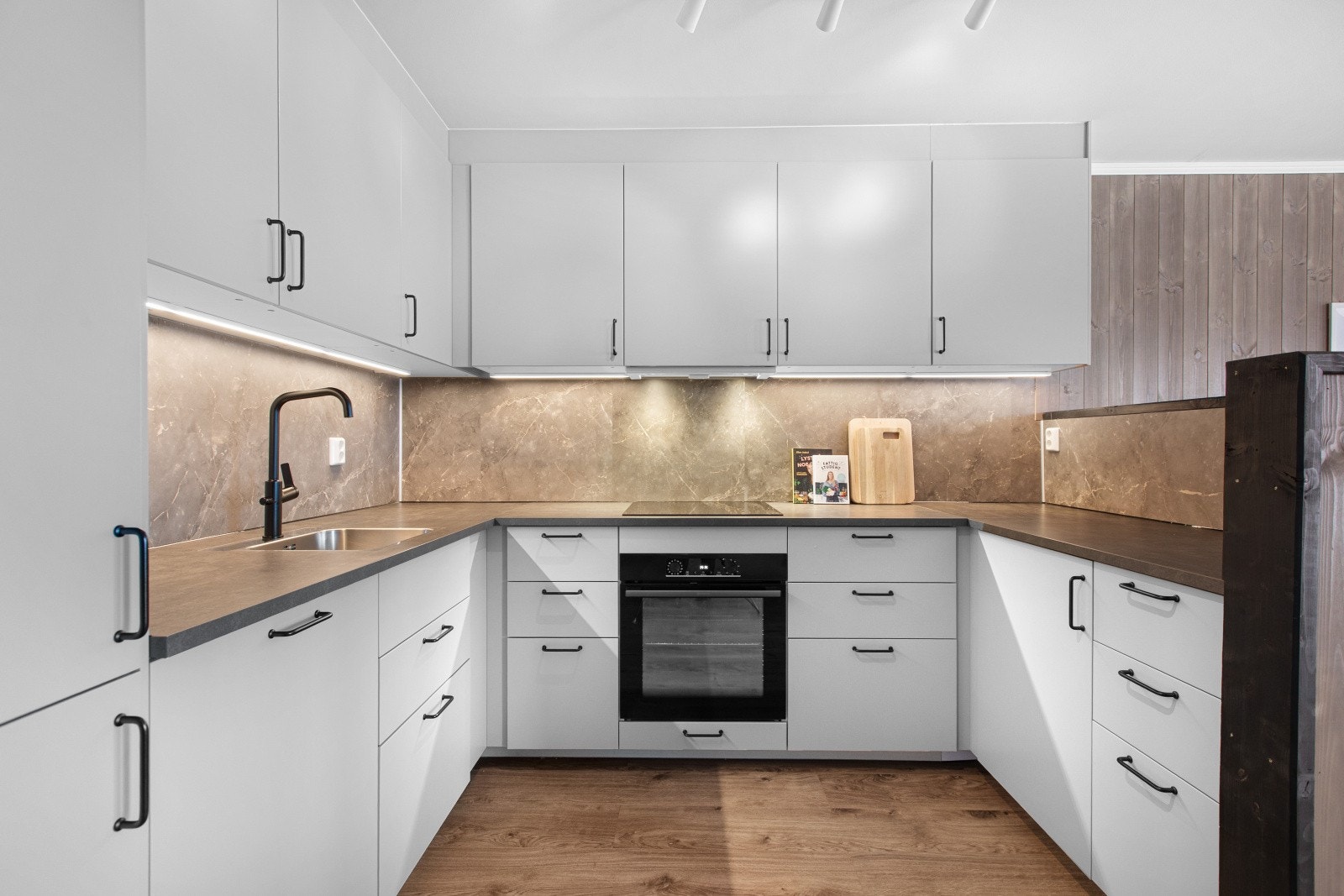 Kjøkkeninnredning med glatte fronter fra 2023, benkeplater i laminat, oppvaskkum med ett-greps blandebatteri og ventilator over kokesonen. Integrerte hvitevarer på kjøkkenet medfølger handelen. Galleribilde