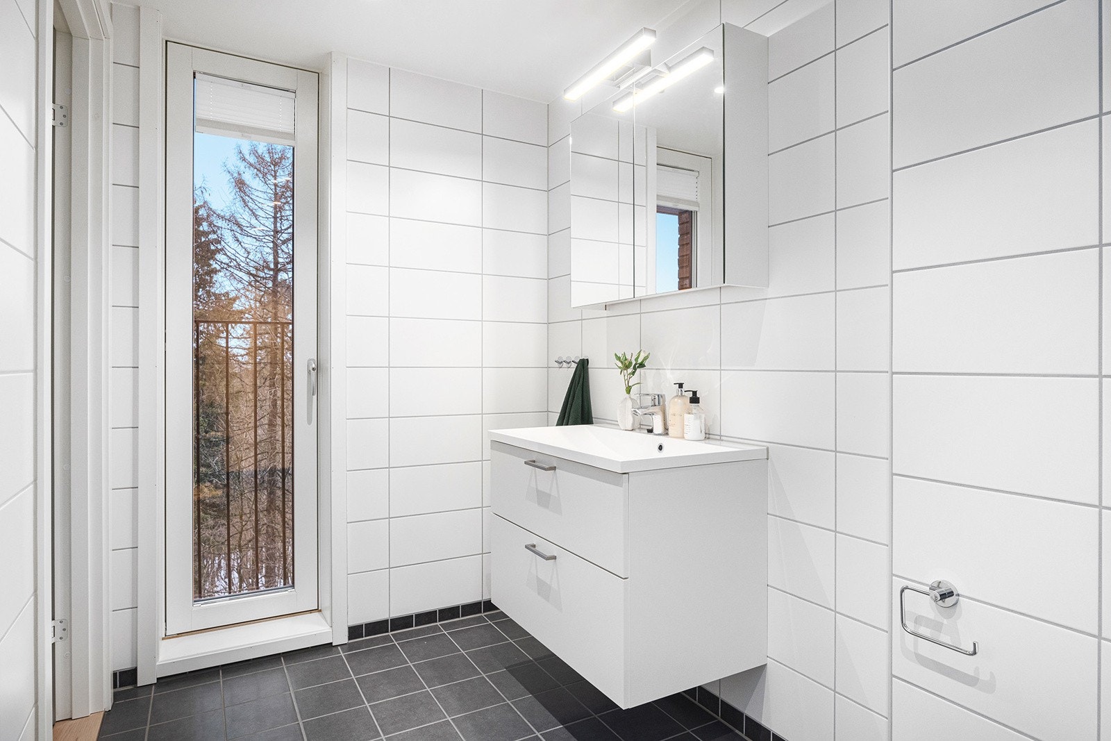 Badet består av dusj, veggklosett, servant med underskap, overskap med speilfronter og belysning. Galleribilde