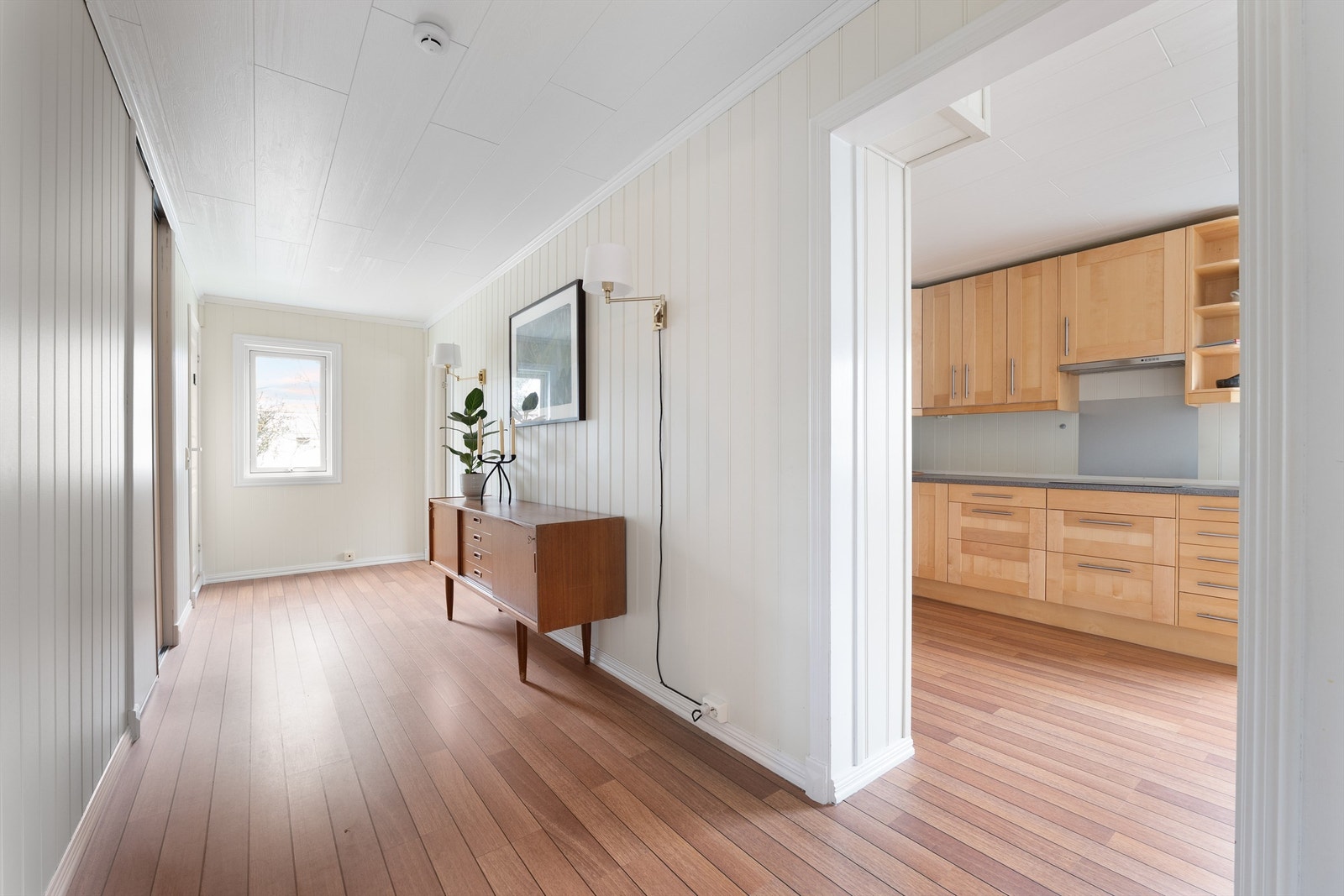 Etasjens soverom og bad er samlet rundt ytre del av gangen, tilbaketrukket fra stuen og kjøkkenet. Vinduet i enden fyller gangen med naturlig lys. Galleribilde