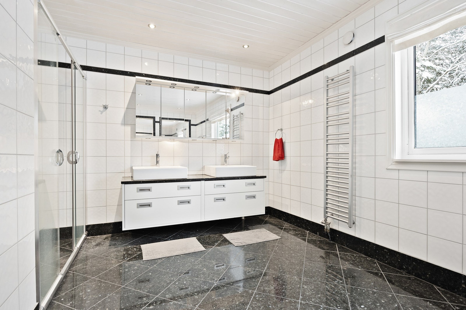 Badet er innredet med dobbel servant, vegghengt skap med glatte fronter og overskap med speil og belysning Galleribilde