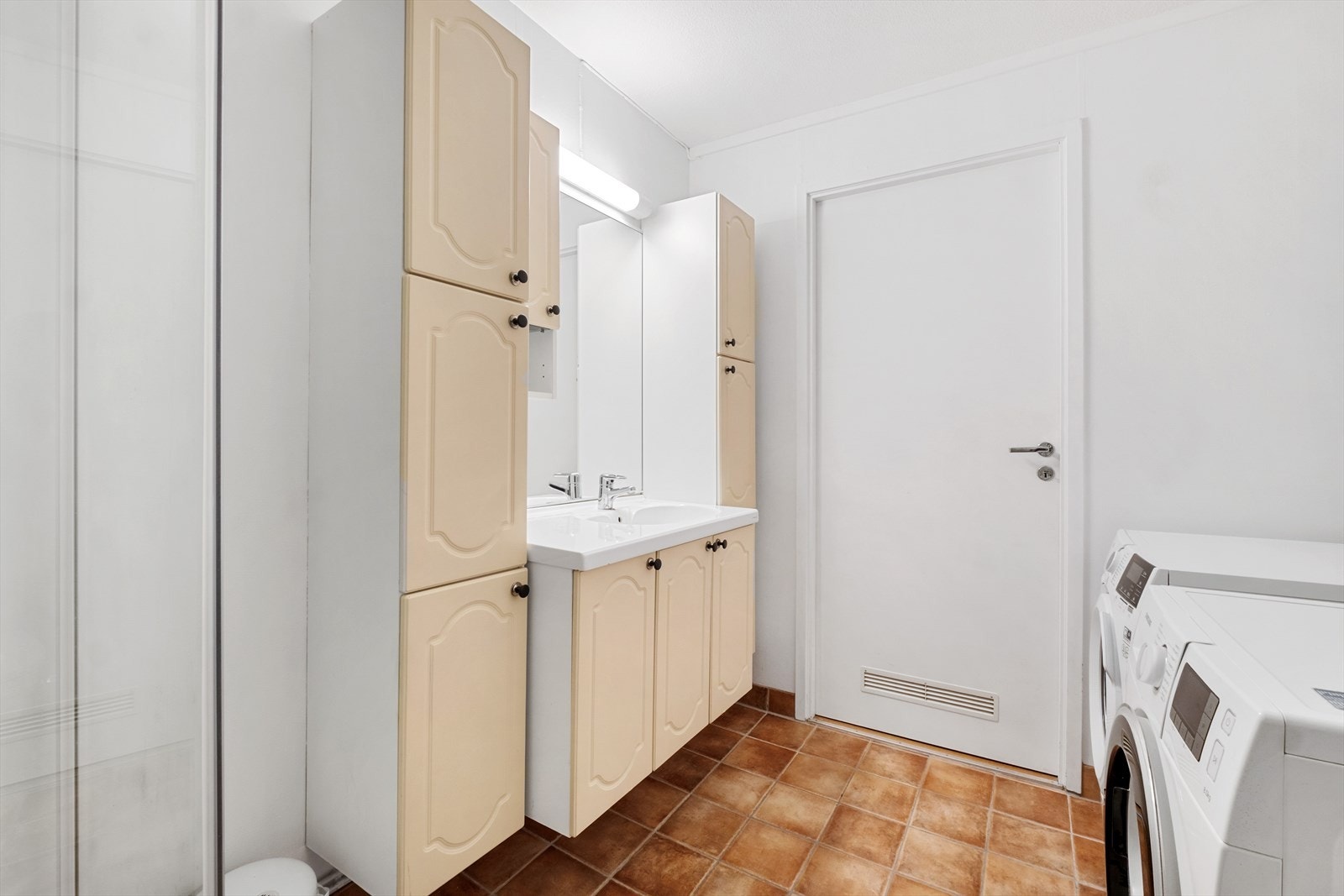 Funksjonelt og velholdt bad med flislagt gulv og lyse overflater - opplegg for vaskemaskin Galleribilde