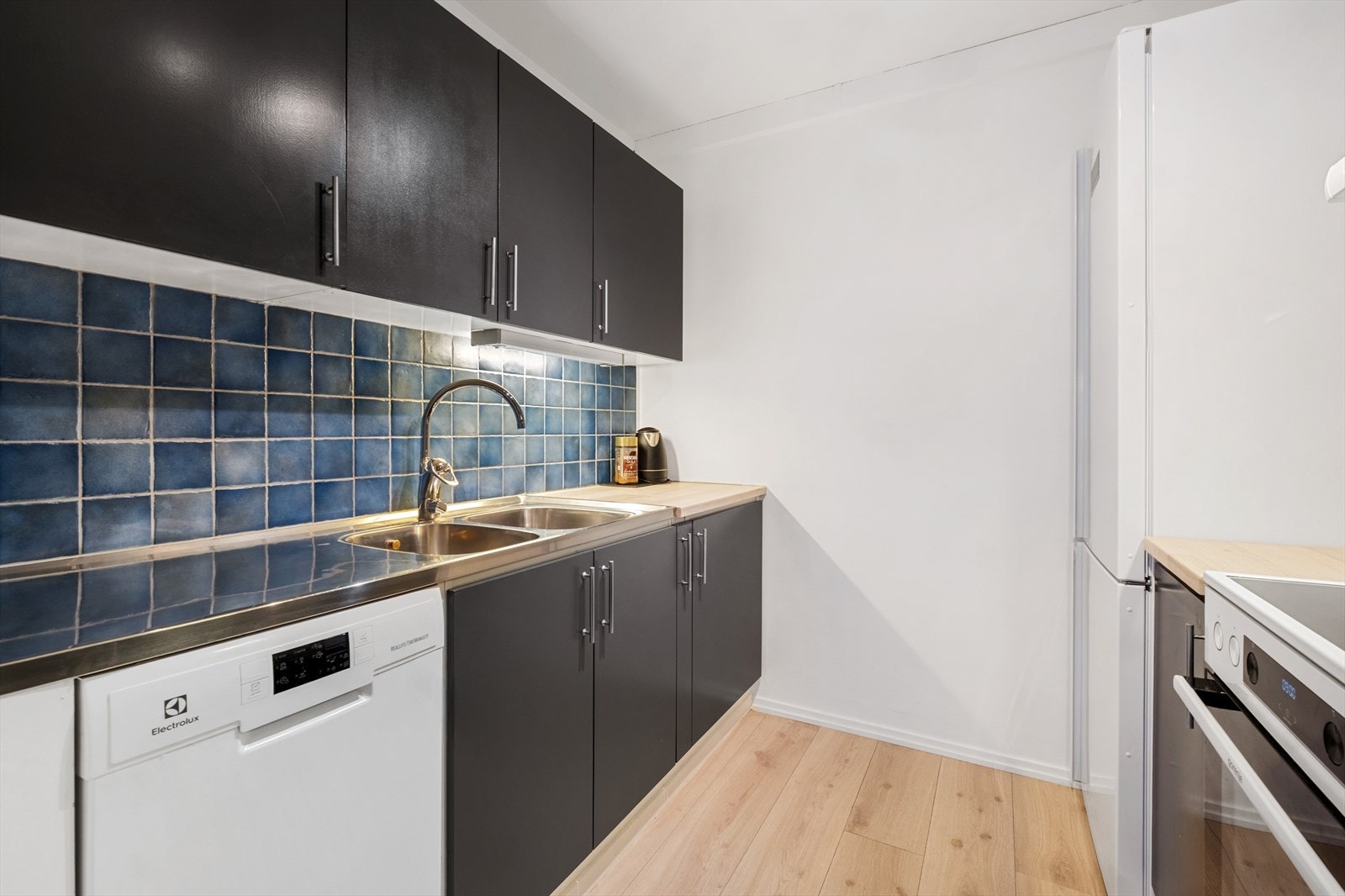 Kjøkkenet er utstyrt med kombinert kjøl- og fryseskap, oppvaskmaskin, komfyr og vannstoppsystem Galleribilde