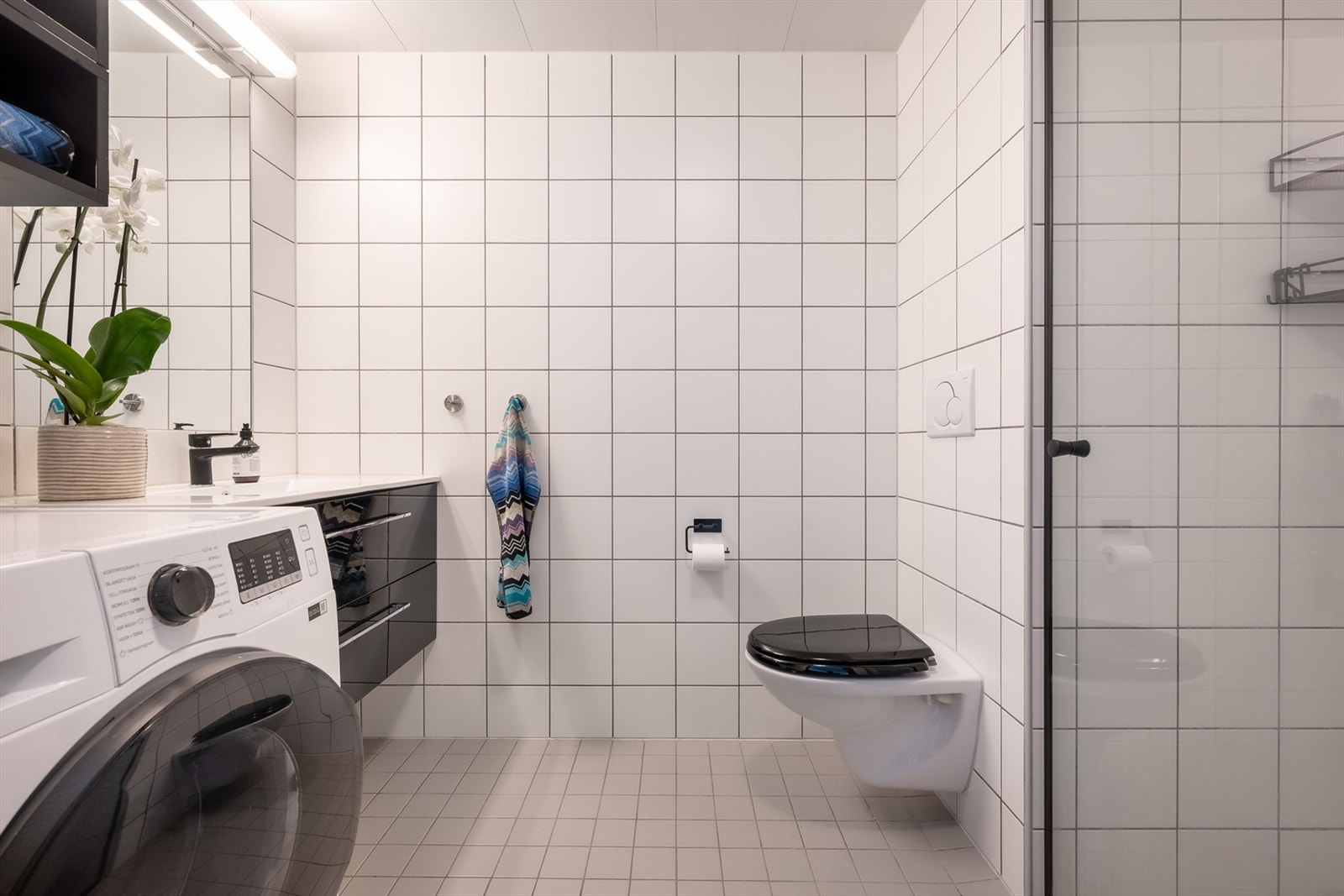 Lyst, flislagt badeværelse fra 2005. Baderomsmøbel med helstøpt vask og skuffer (fra 2020). Mekanisk avtrekk med innluft under dør. Opplegg for vaskemaskin. Galleribilde