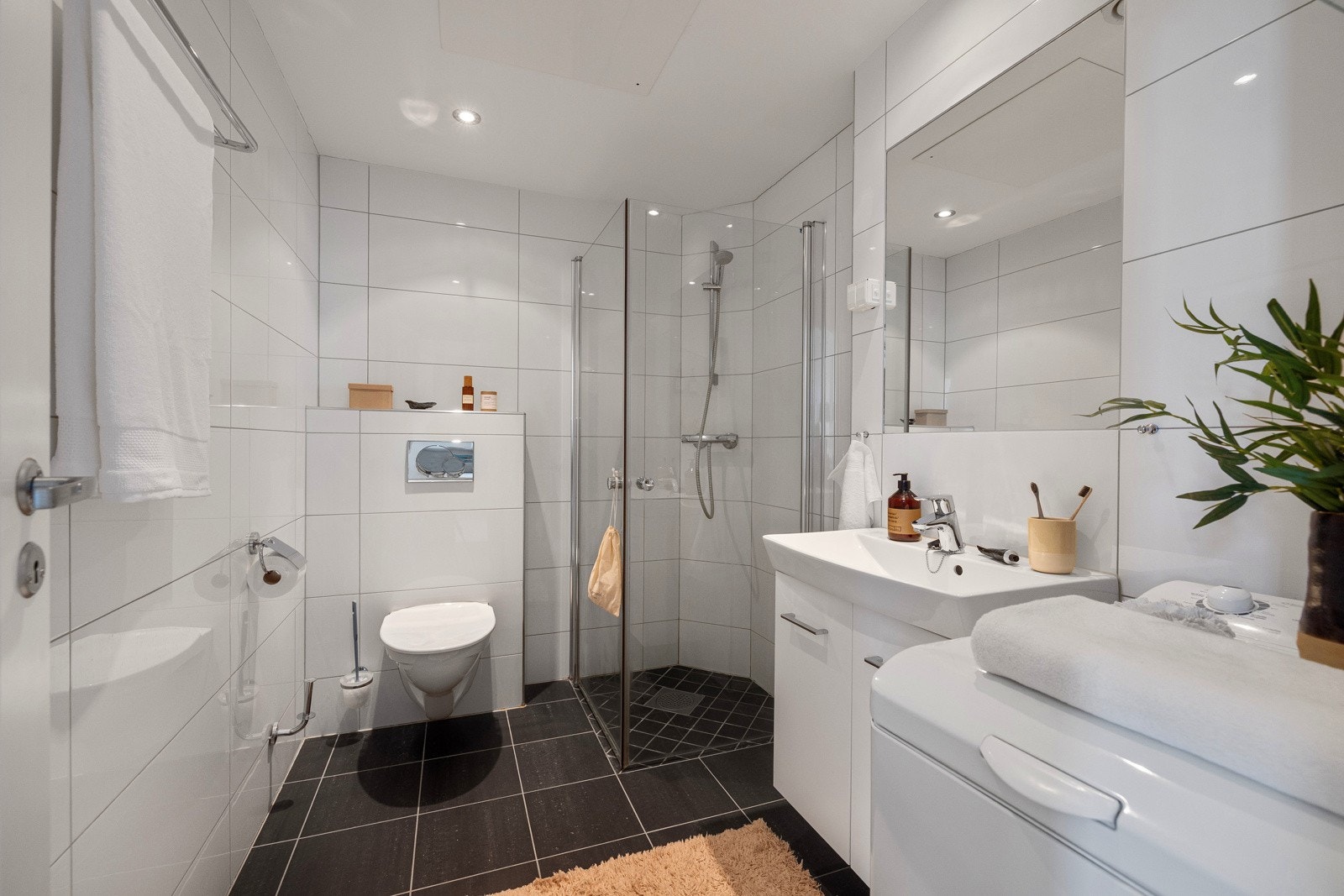 Det er utstyrt med toalett, dusjhjørne med glassdører, samt et praktisk servantskap med hvit keramikkservant og ettgreps blandebatteri fra Hans Grohe. Galleribilde