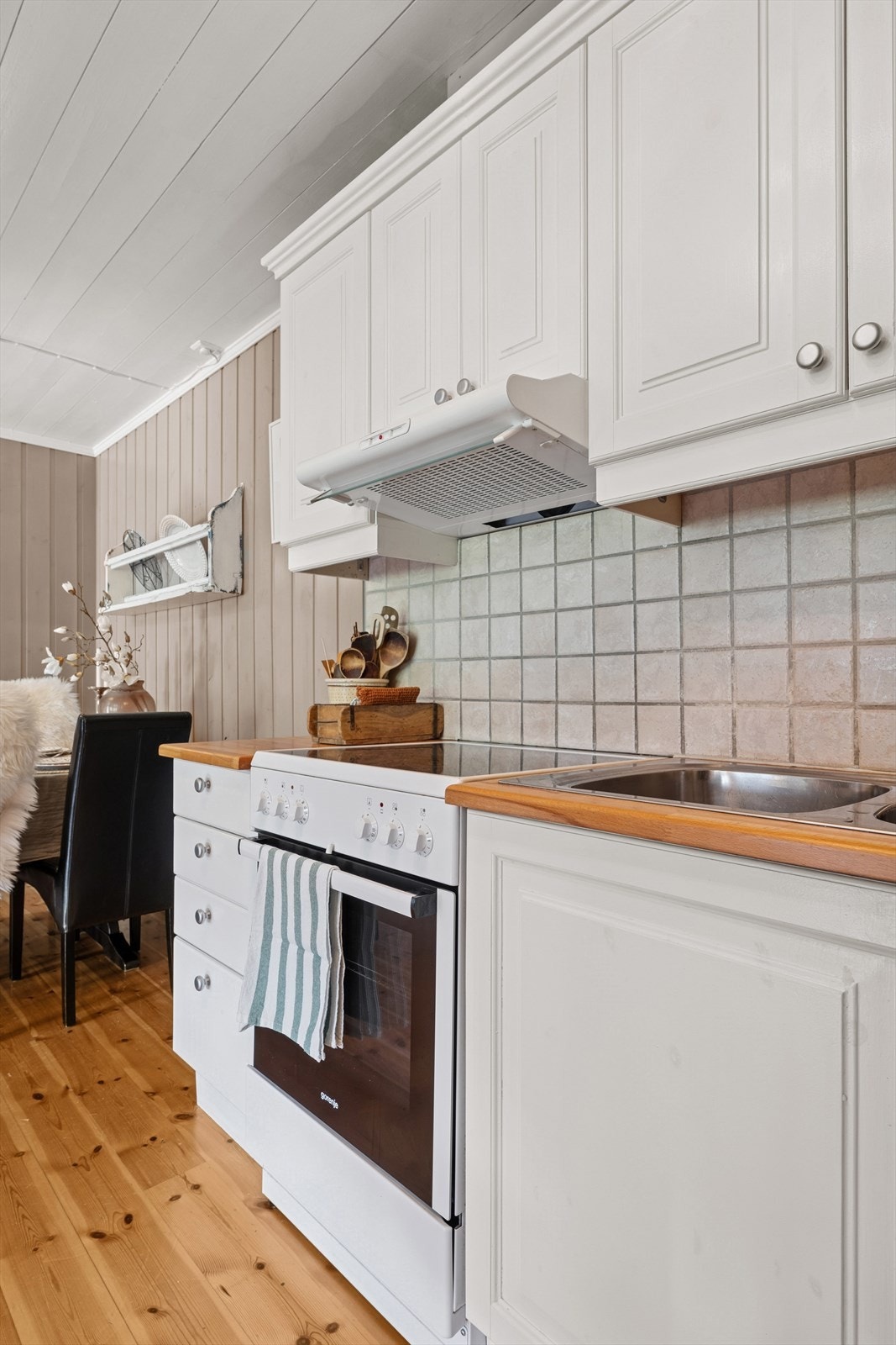 Køkkeninnredningen er pent utført med hvite, profilerte fronter og heltre benkeplate med kjøkkenkum. Galleribilde