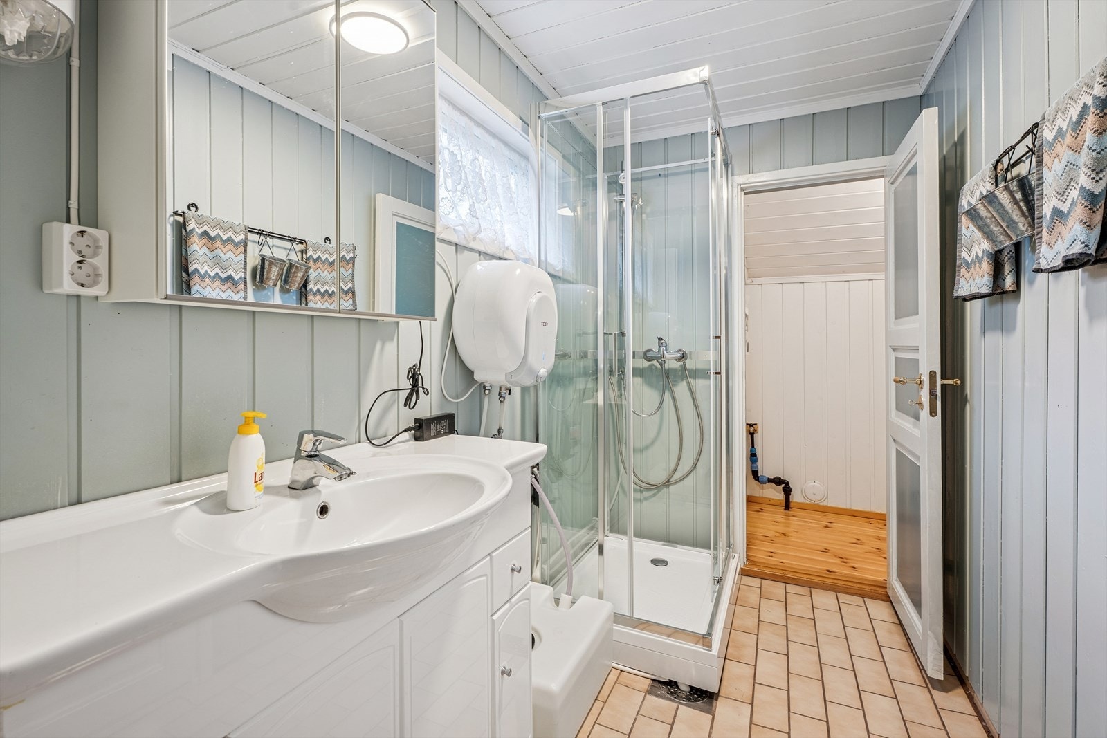 Praktisk dusjkabinett og flislagt gulv med varmekabler på badet. Galleribilde