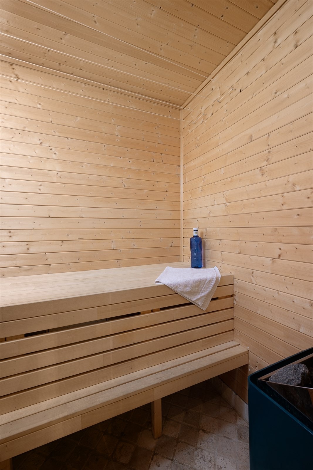 Romslig badstue med flislagt gulv og panelte vegger/tak. Plassbygget sitte/liggebenk. Elektrisk badstuovn. Galleribilde