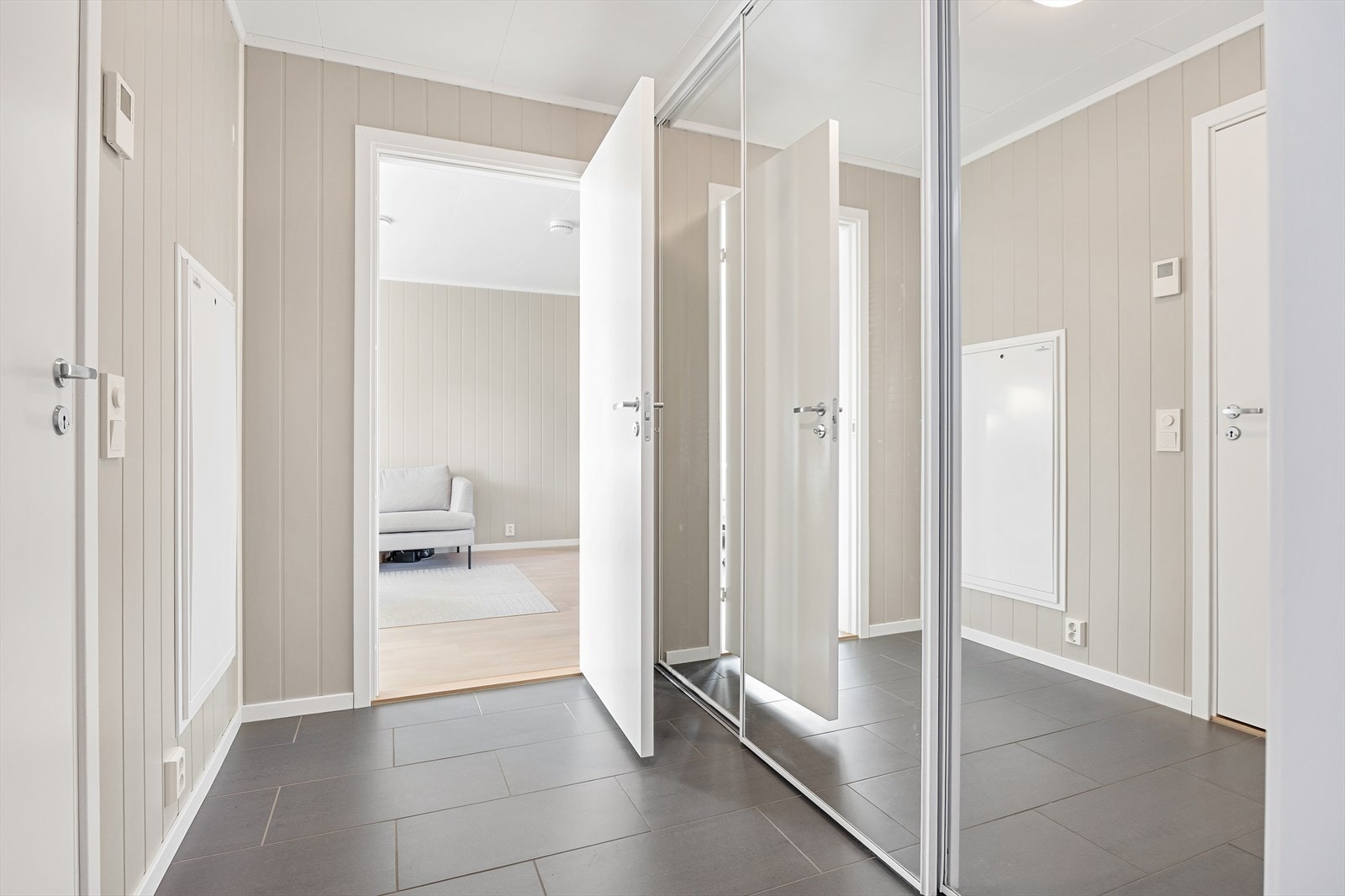 Gang med flislagt gulv og stor skyvedørsgarderobe med speilfronter - godt med oppbevaringsplass. Galleribilde