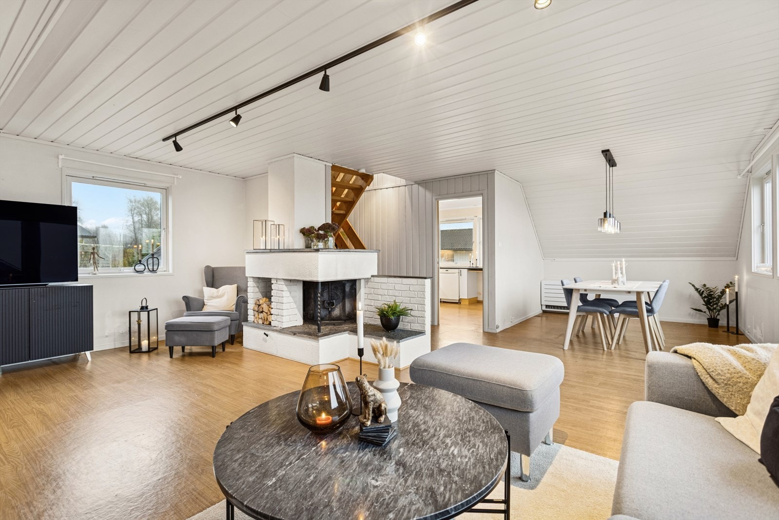 Romslig og lys stue med god plass til både sofagruppe og spisebord. Midt i rommet med peisovn som skaper en lun og hyggelig atmosfære. Galleribilde