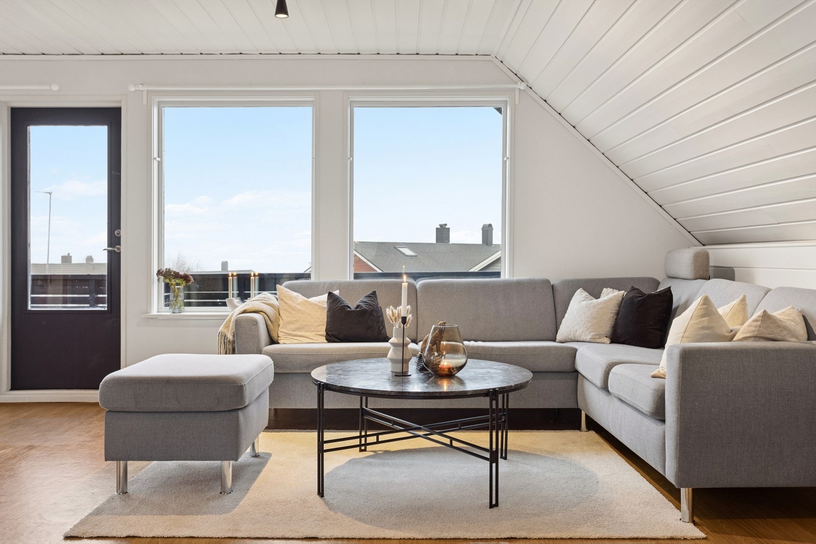 Lys stue med sofagruppe, store vindusflater som slipper inn rikelig med dagslys og med direkte utgang til balkong. Galleribilde