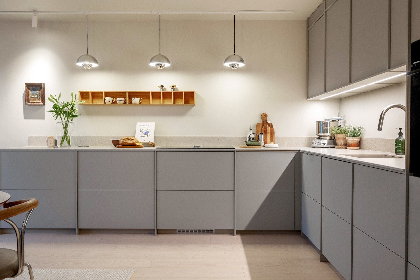 Kjøkkeninnredningen har glatte, fabrikklakkerte fronter, keramisk benkeplate og backsplash, samt underlimt kum i kompositt Galleribilde