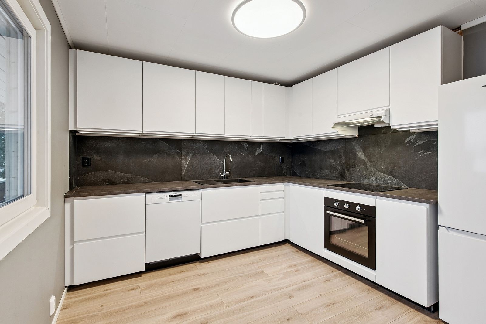 Kjøkkenet har godt med skap- og benkplass og har alt av hvitevarer Galleribilde