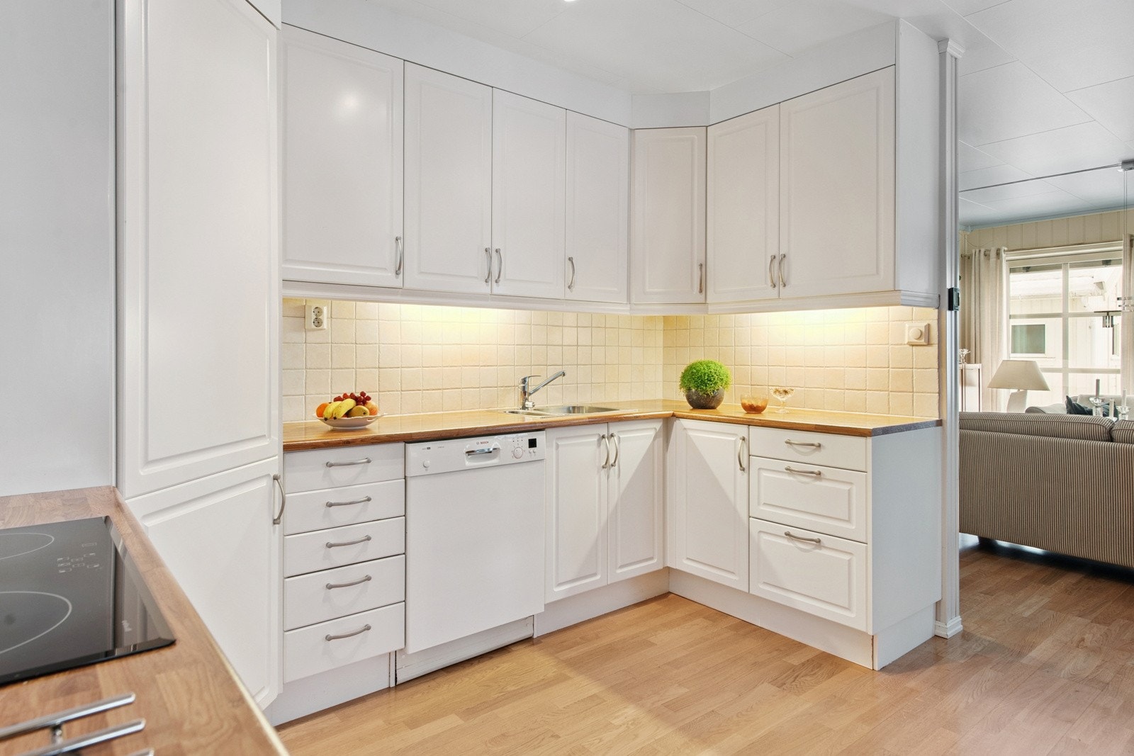 Kjøkken med lyse, profilerte fronter og laminert benkeplate og fliser i benkeryggen. Galleribilde