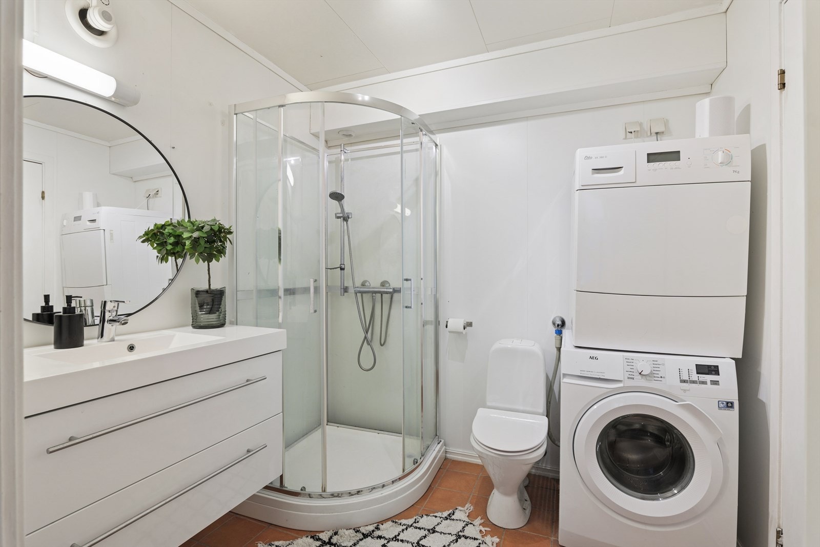 Bad/wc/vaskerom utstyrt med toalett, innredning med servant, dusjkabinett og opplegg for vaskemaskin. Galleribilde