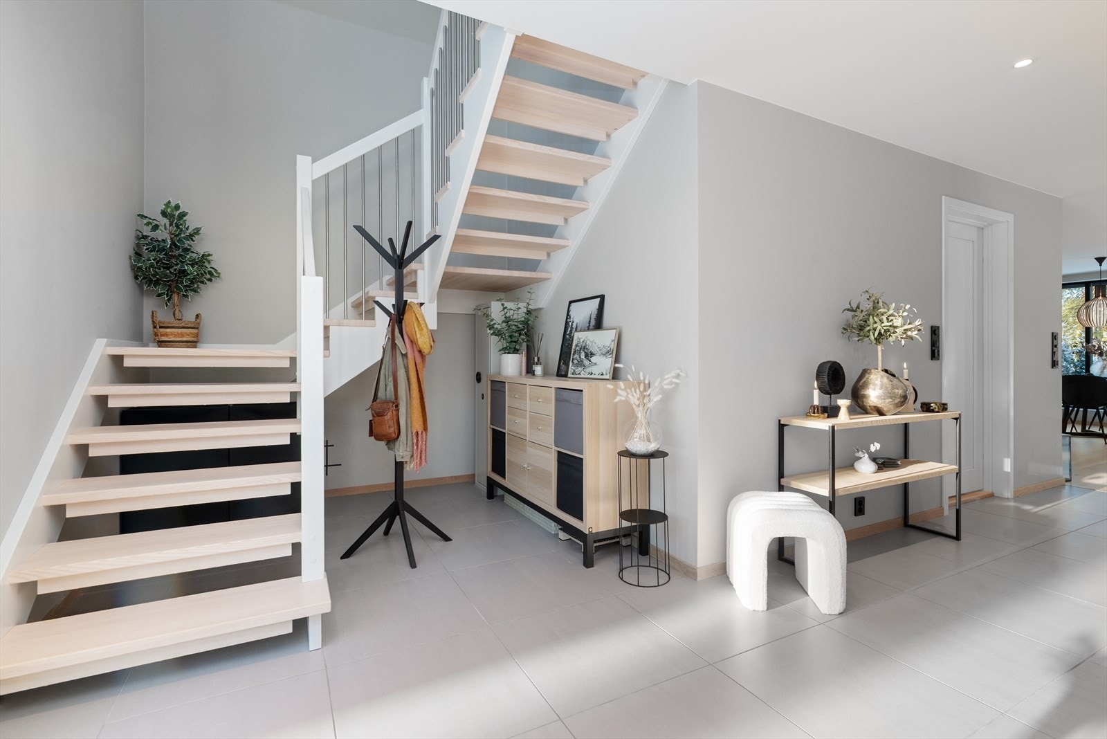 Overflater består av store, praktiske flis på gulv, slette gipsvegger i malt utførelse med listefri overgang til malte gipsplater i tak med downlights. Fra entré er det videre adkomst til stue med åpen kjøkkenløsning. Galleribilde