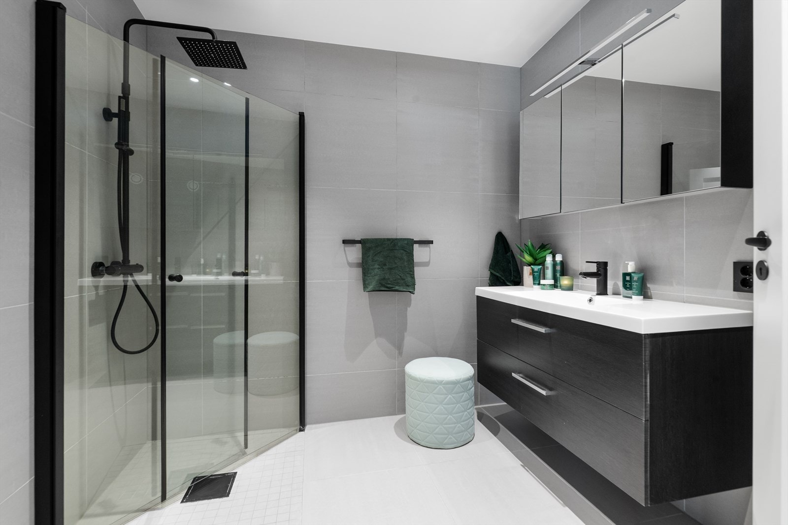 Mørk og pen innredning med fronter i slett utførelse og heldekkende servant, overskap med speilfronter og overlys. Galleribilde