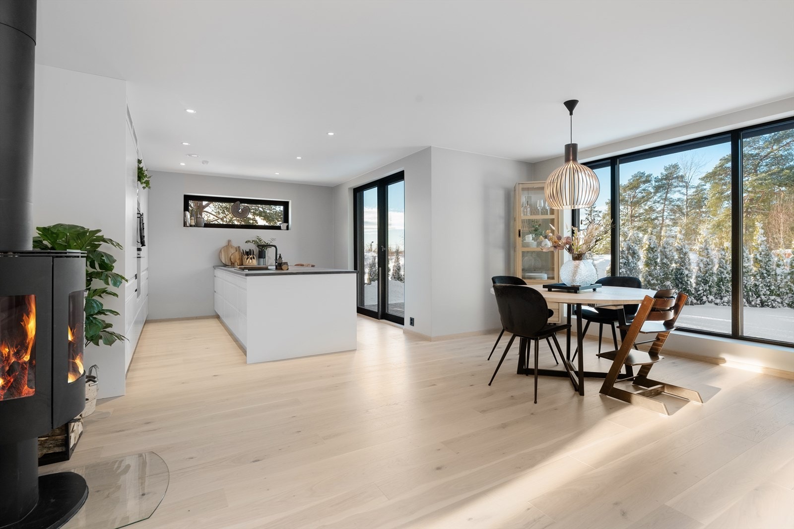 Innbydende og moderne kjøkkendel med hvit, takhøy innredning og stor, kjøkkenøy med svært god oppbevaringsplass. Kjøkkenløsningen her gjør det enkelt å drive med matlaging samtidig som man har oversikt over barna eller kan sosialisere med gjester. Galleribilde