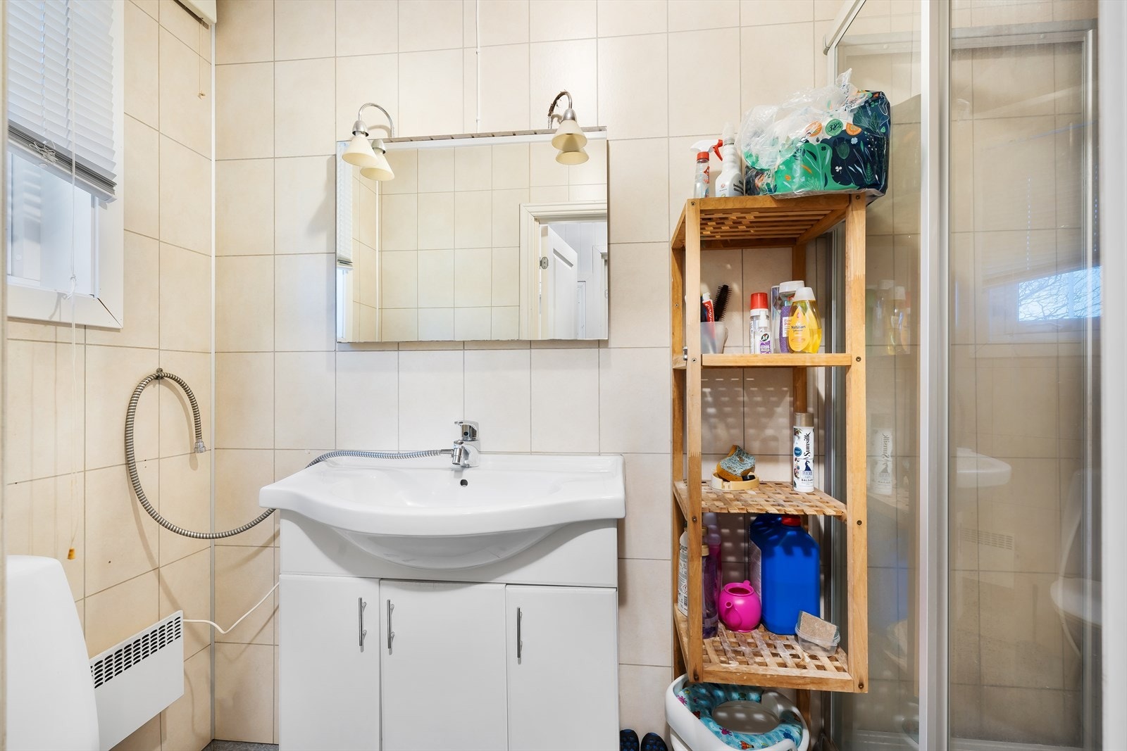 Leil. 1 - Badet har et servantskap med heldekkende servant, speil og belysning. Det er montert et dusjkabinett og et toalett. Her er det satt inn et nytt vindu i 2025. Galleribilde