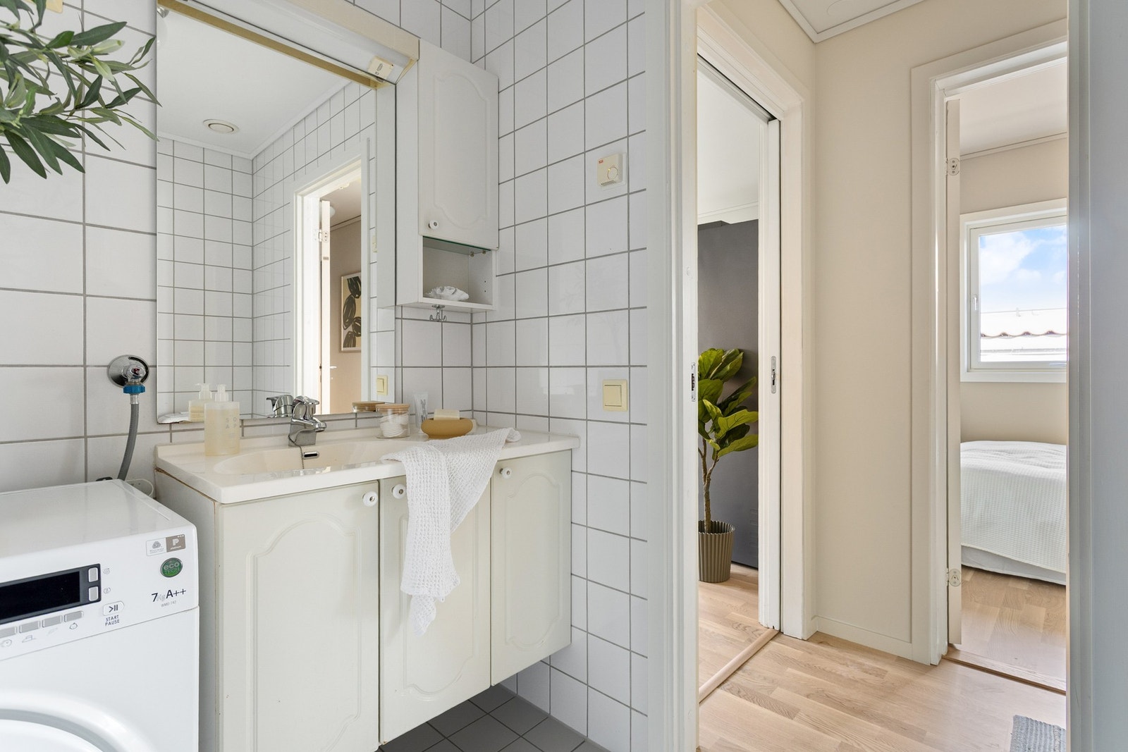 Videre har du servant på underskap, veggskap, speil med overbelysning og opplegg for vaskemaskin. Galleribilde