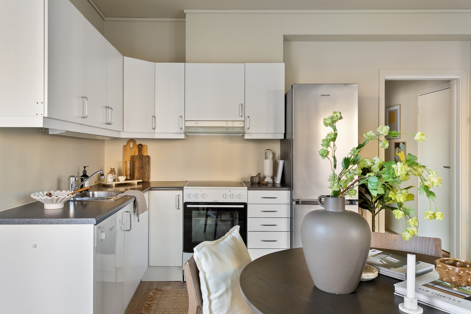 Lys, glatt kjøkkeninnredning fra byggeår med laminat benkeplate og kum i rustfritt stål. Galleribilde