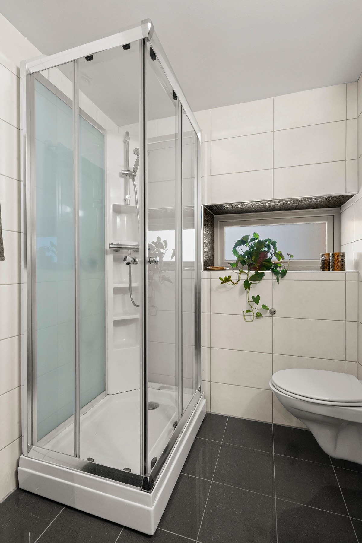 Badet er utstyrt med dusjkabinett og kombi vask/tørk maskin fra AEG som medfølger Galleribilde