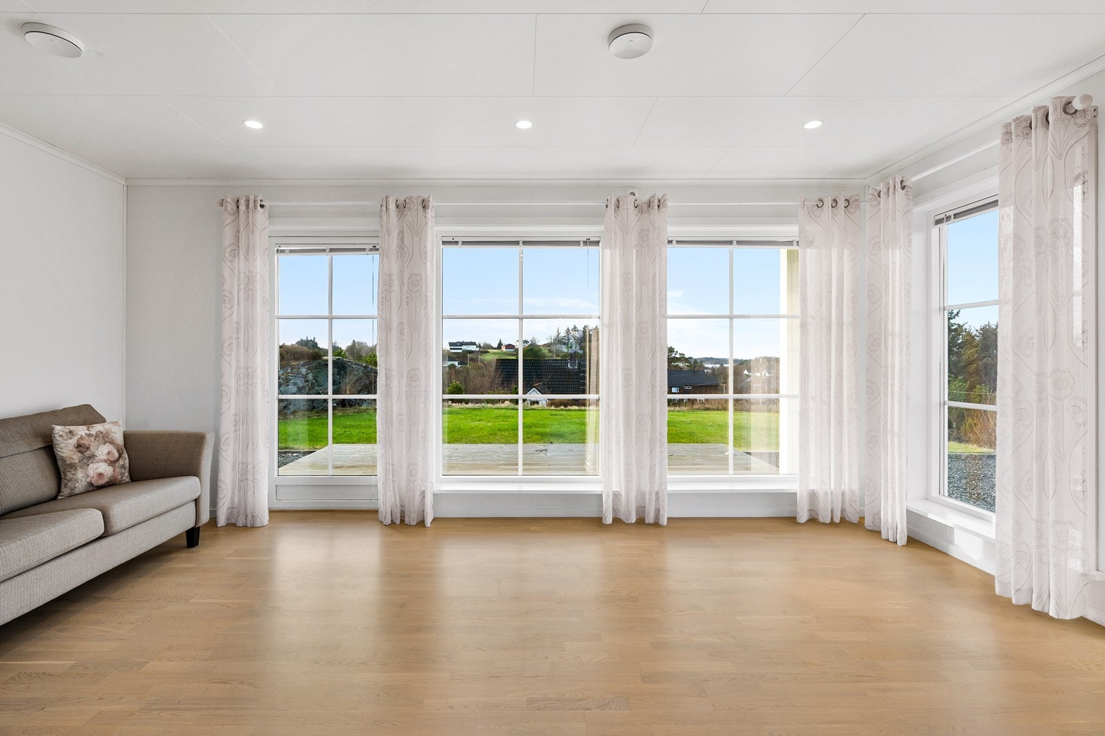 Boligens stue er lys og innbydende med store vinduer Galleribilde