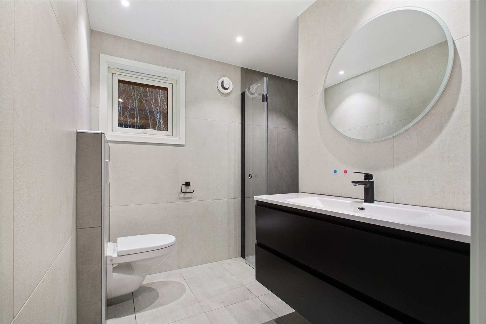 Stilrent bad med store, pene fliser og mørke detaljer som gir rommet et moderne "look" Galleribilde