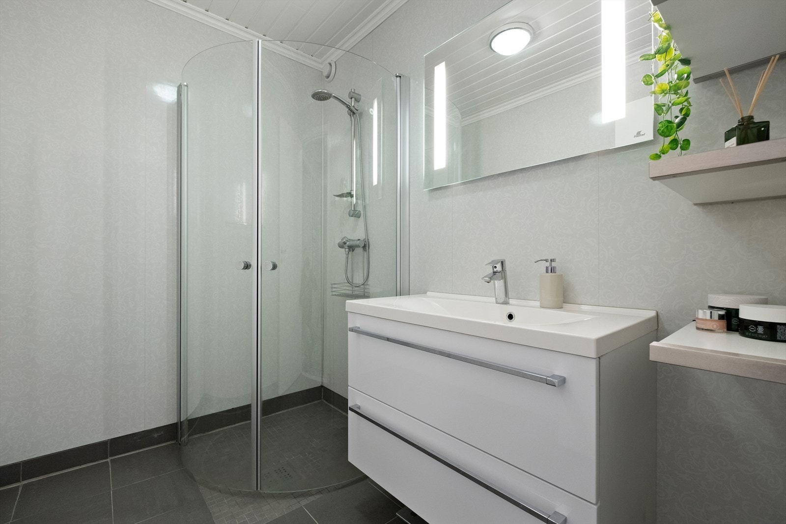 Badet er utstyrt med nedfelt servant med speil over og dusjvegg av glass. Galleribilde