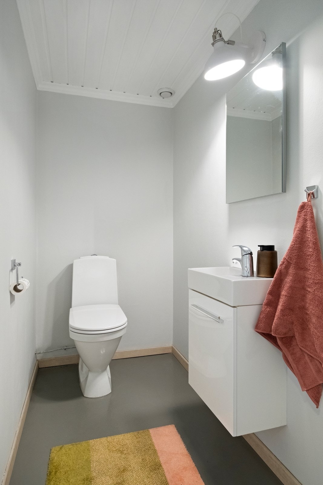 Toalettrom med gulvstående toalett og vegghengt servant. Galleribilde