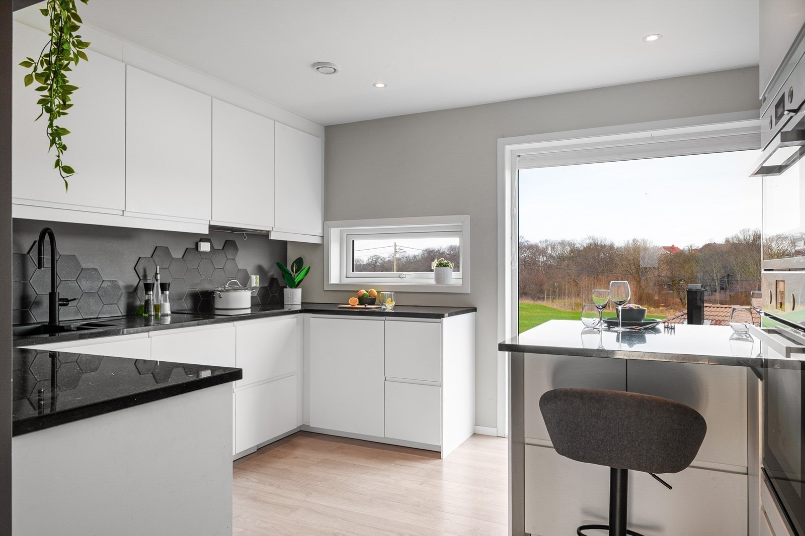 Et tidløst kjøkken med lyse, glatte overflater og en praktisk kjøkkenøy. Galleribilde