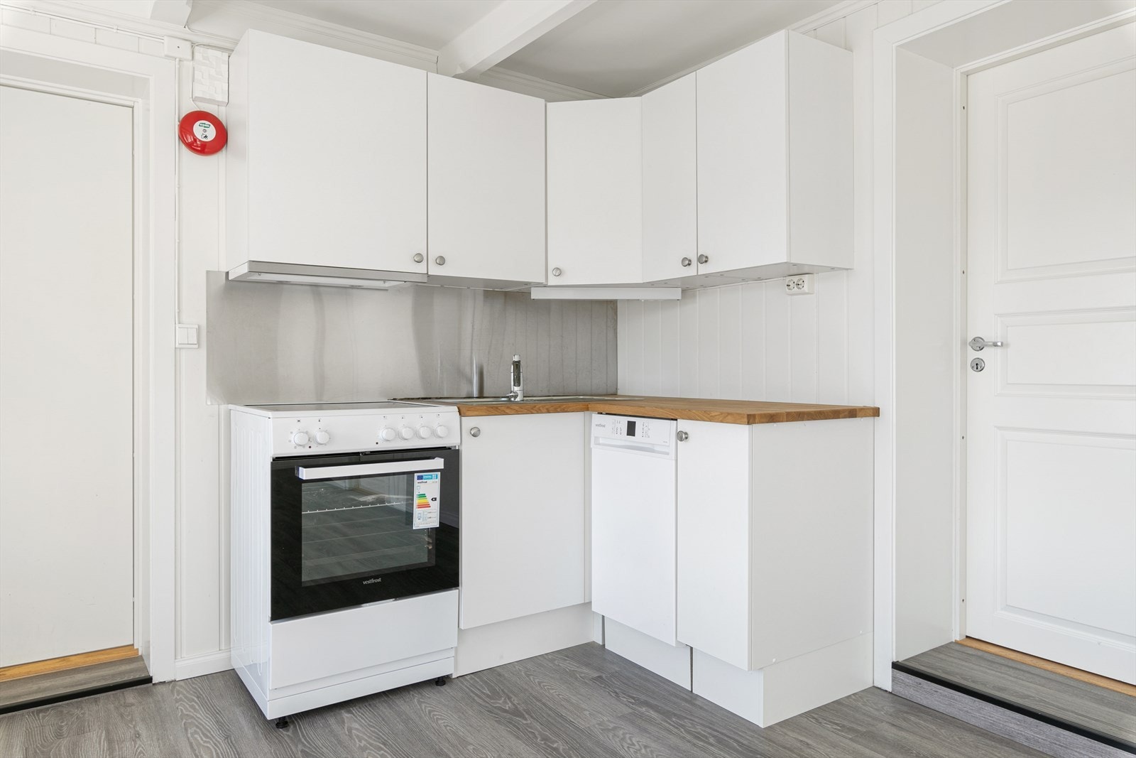 Kjøkkeninnredning med hvite, glate fronter, oppvaskbenk med nedfelt stålbeslag. Galleribilde