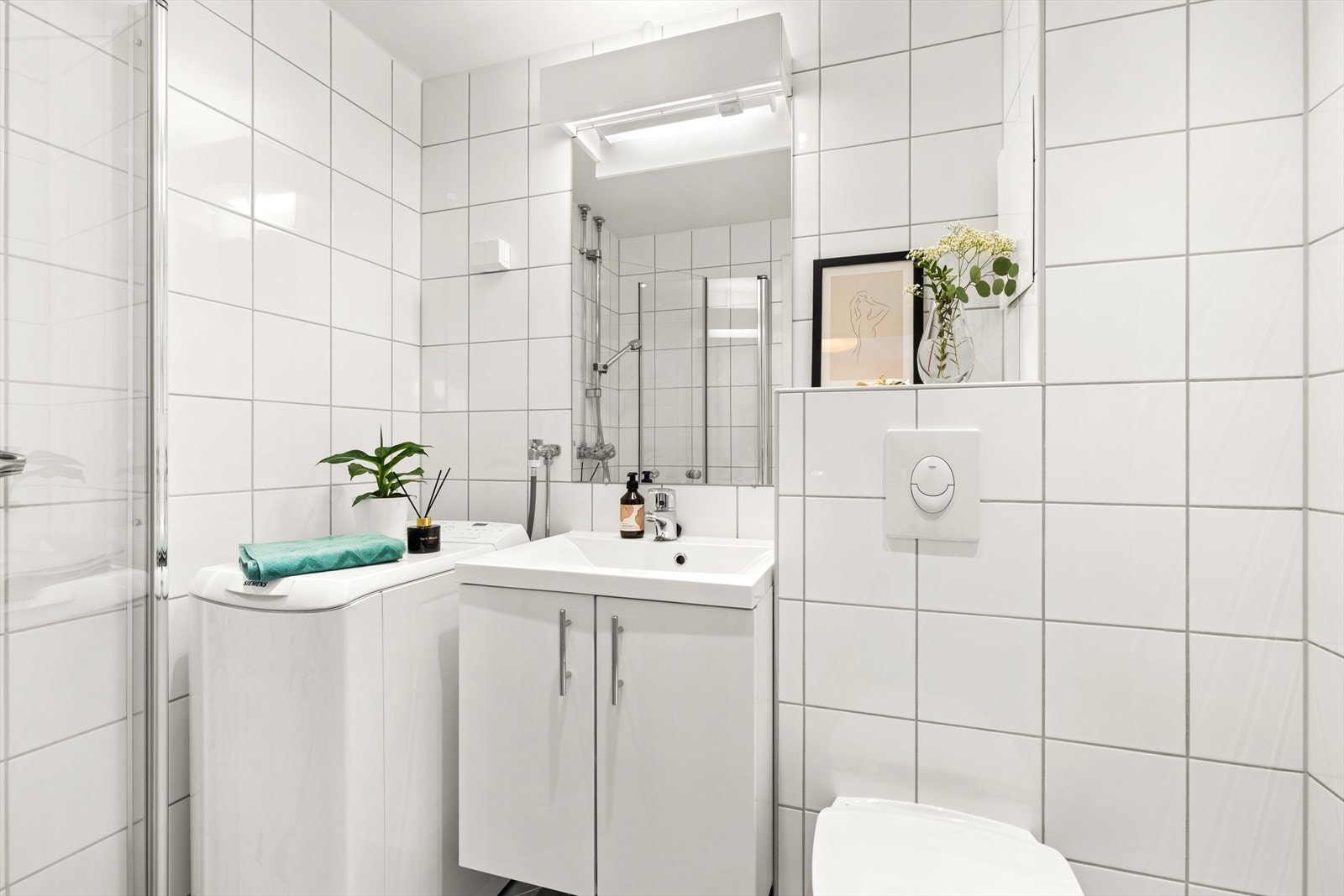 Pent, flislagt bad med varmekabler i gulv. Badet er innredet med servant m/underskap, dusjdører i glass og vegghengt toalett. Opplegg for vaskemaskin. Galleribilde