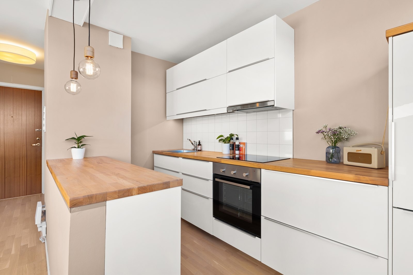 Stue- og kjøkken i åpen løsning. Moderne kjøkkeninnredning med høyglansede fronter og fine detaljer. Galleribilde